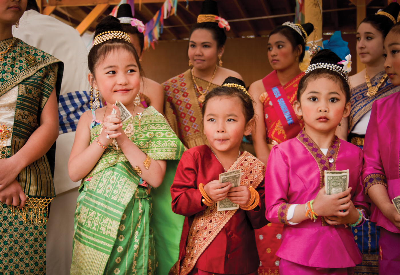 Three young girls, dressed as princess in traditional Lao clothing, pose with teenagers following the Pi Mai princess parade.