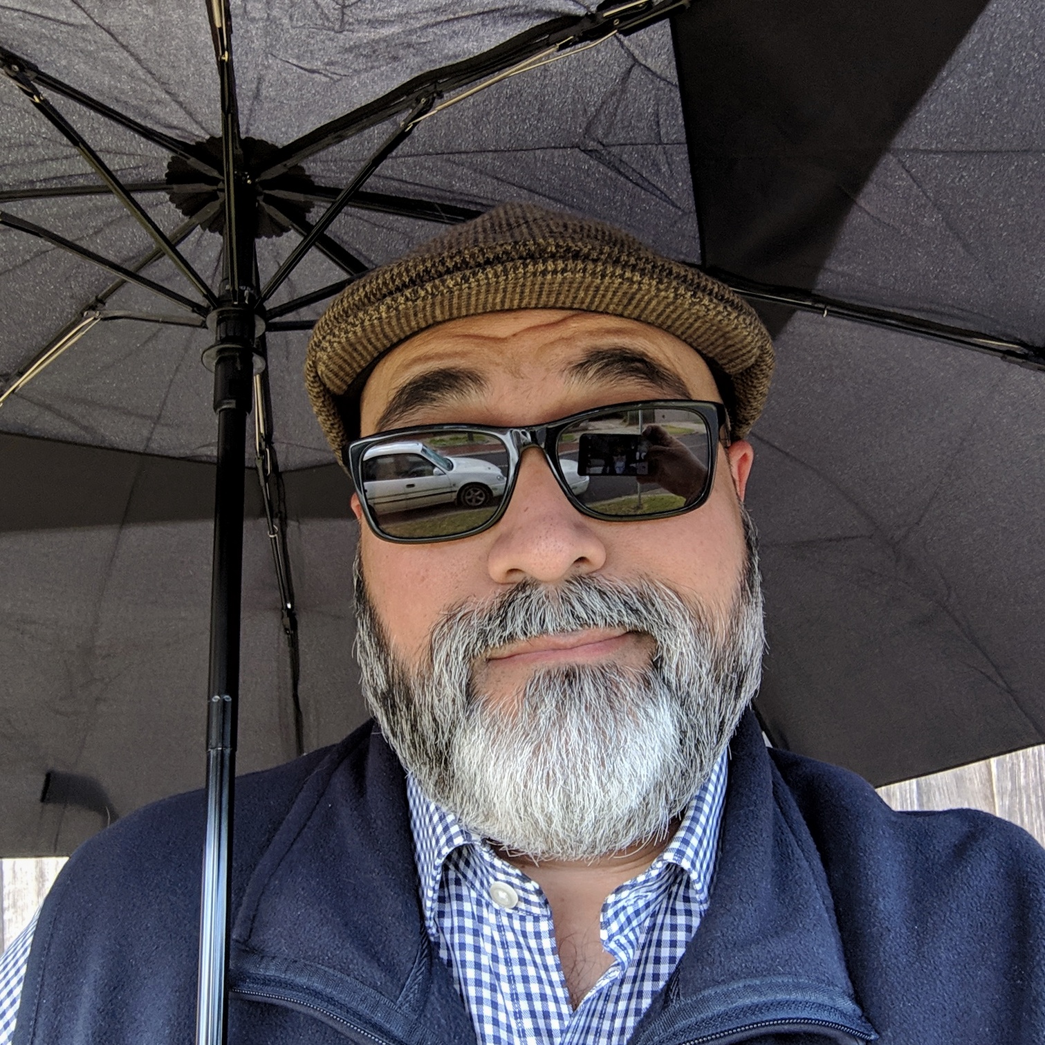 Selfie in sunglasses, sheltering from the rain under an umbrella.