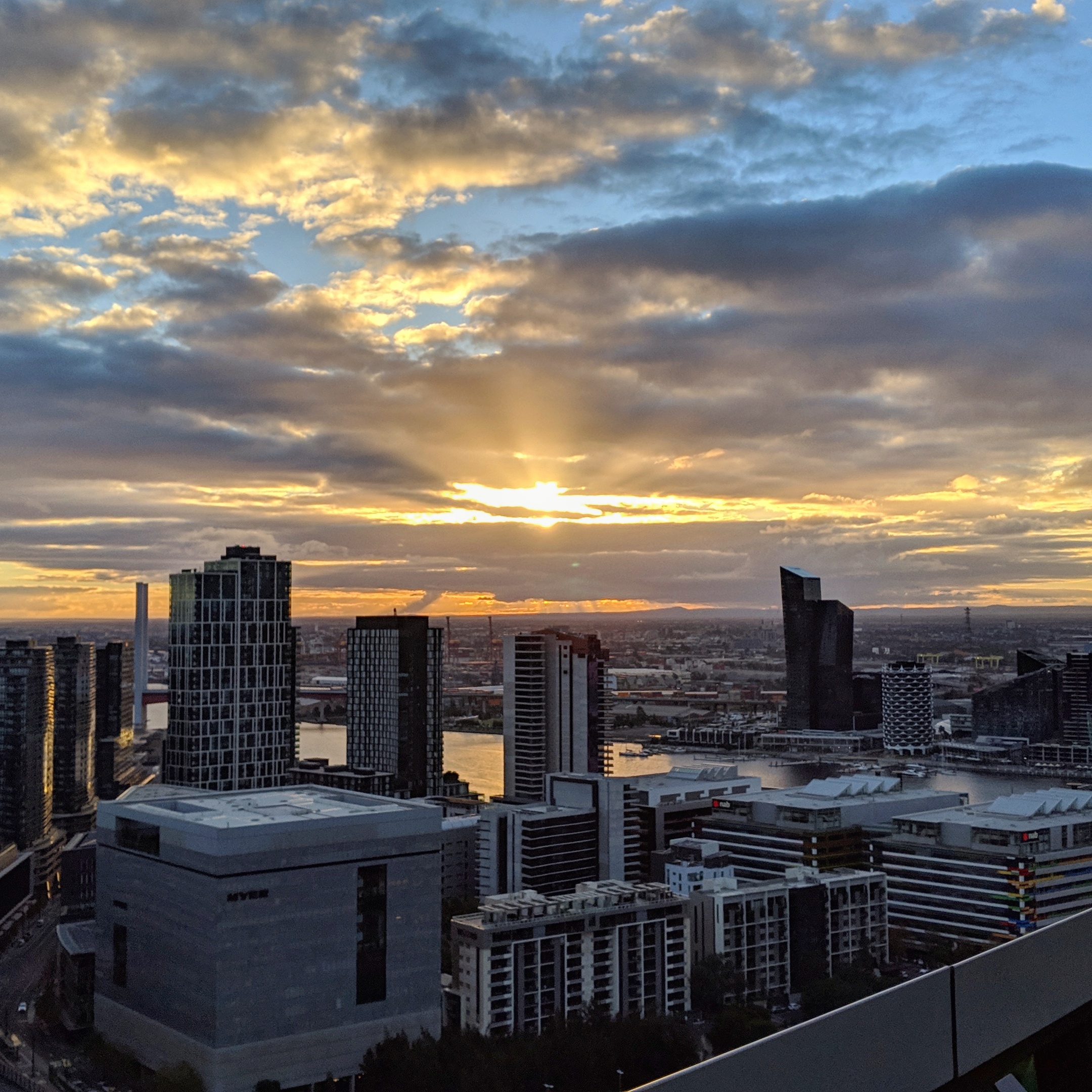 Cityscape showing sun setting behind the clouds.