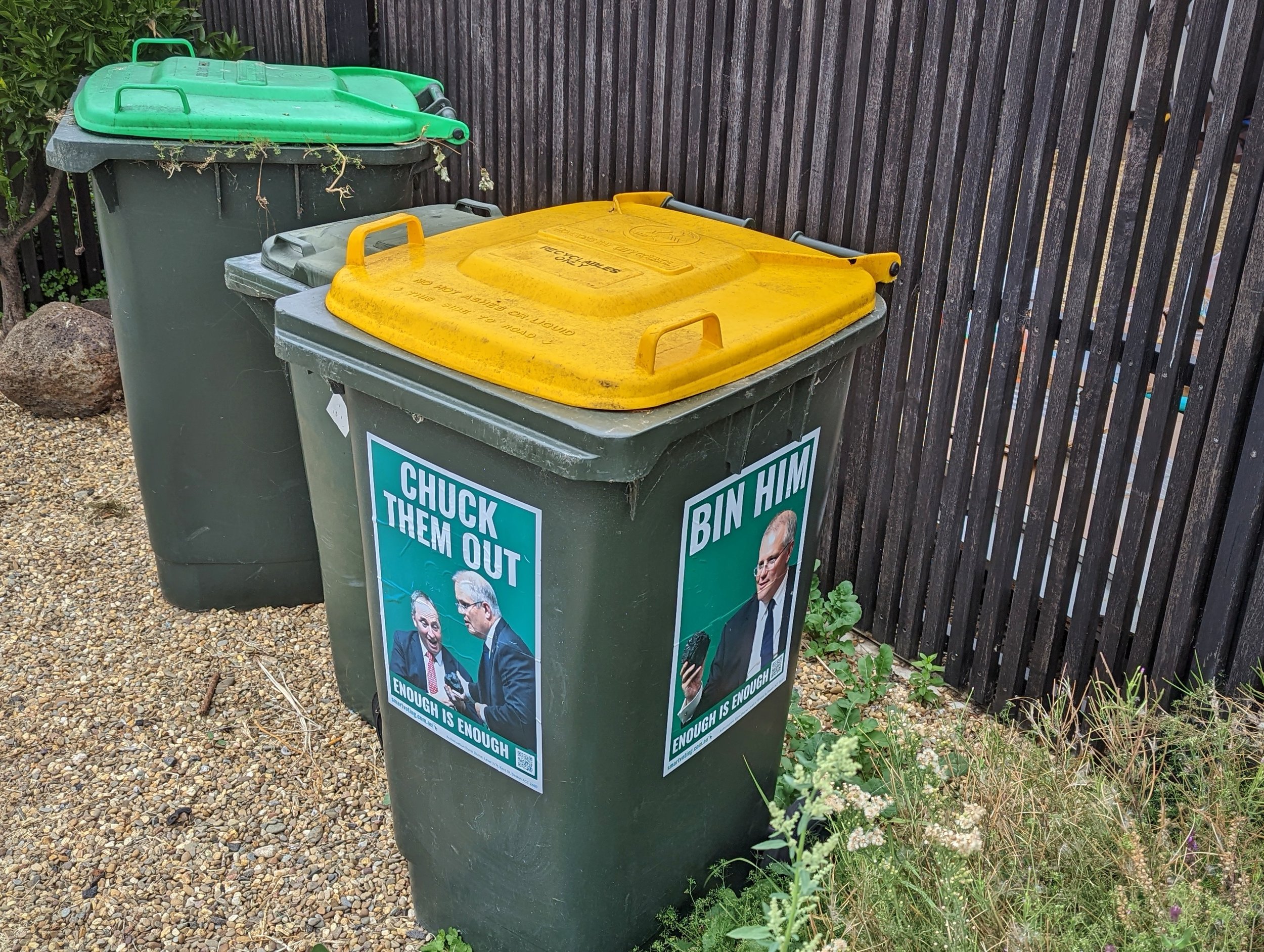  Photo of a large rubbish bin with large stickers on two sides. Both signs show Australian Prime Ministry Scott Morrison. One sign reads “CHUCK THEM OUT” and the other “BIN HIM”.  