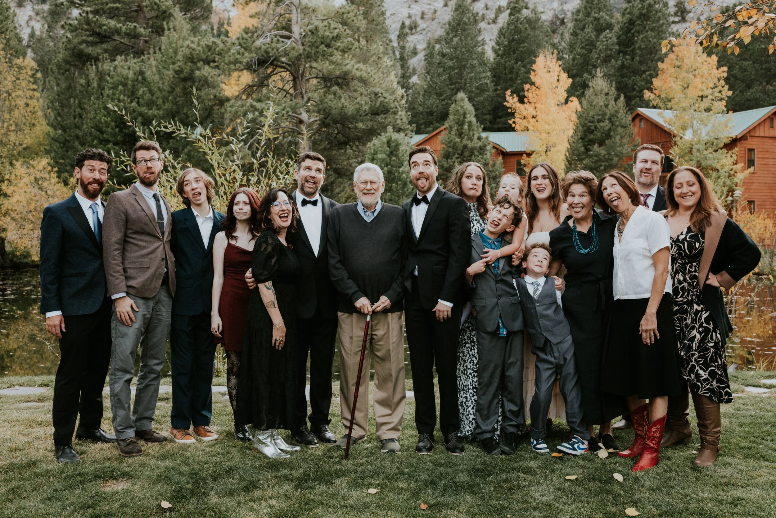 Group of family and friends outdoors, celebrating, with autumn trees and wooden cabins in the background in Mammoth, CA by Dorey Kronick