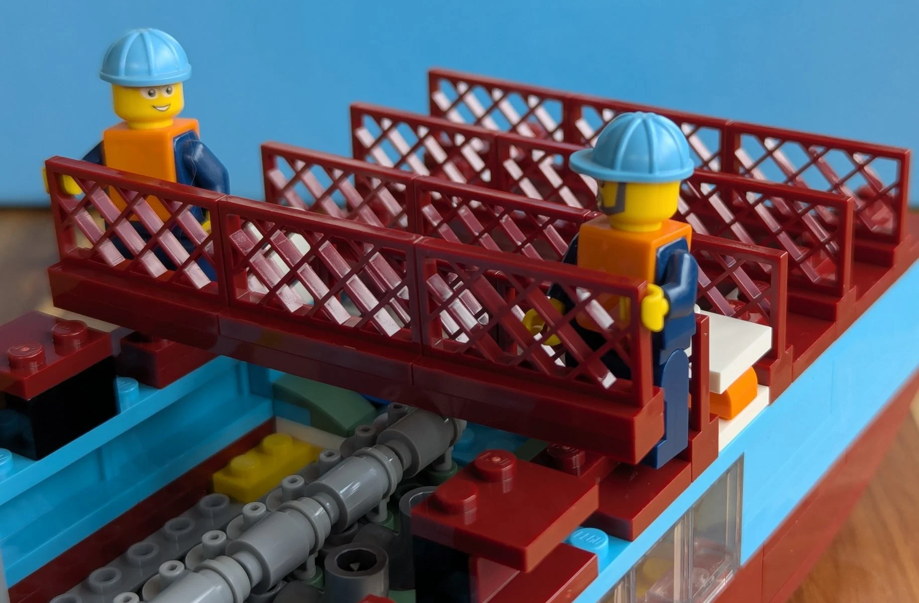 Minifigure construction workers placing dark red fences.