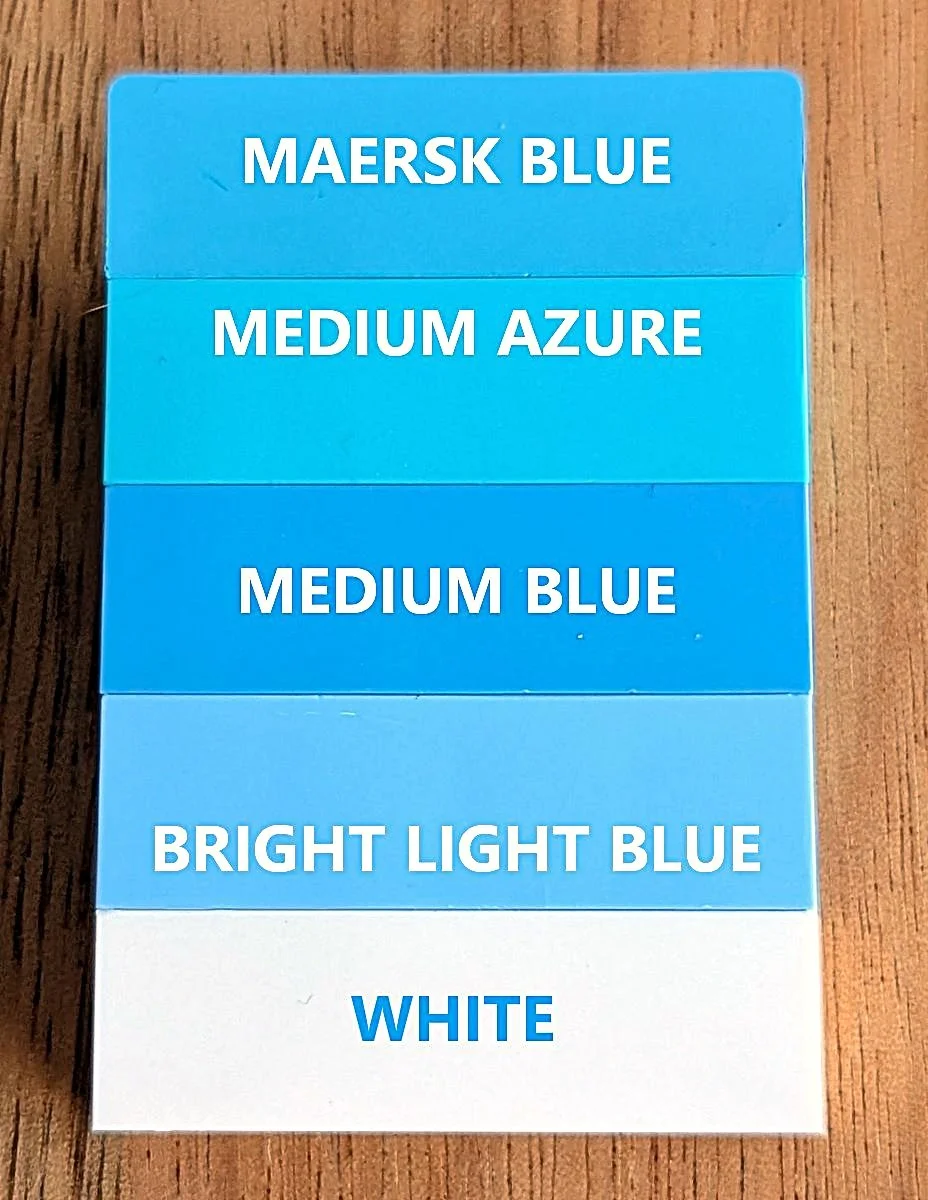 Five LEGO bricks, comparing white and four shades of blue.
