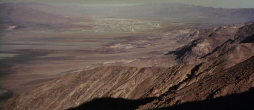 EXT. TATOOINE - BLUFF OVERLOOKING MOS EISLEY SPACEPORT - DAY