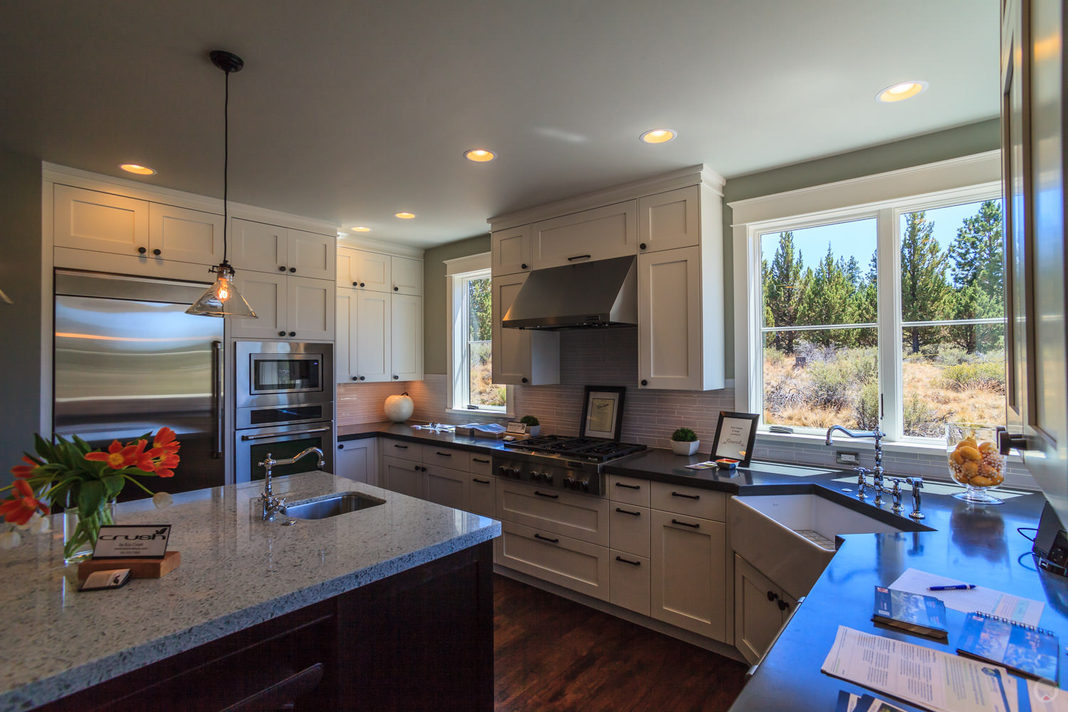 Stainless steel appliances. Also note: Shaker-style cabinets, subway tile backsplash, farm sink, and pendant light fixture.