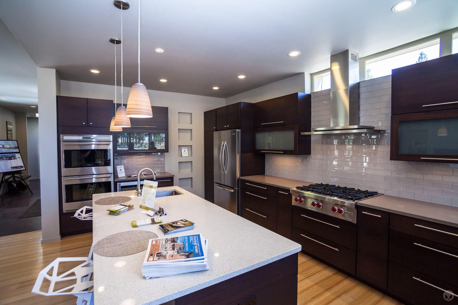 A backsplash of subway tiles. Also note: pendant light fixtures and stainless steel appliances.