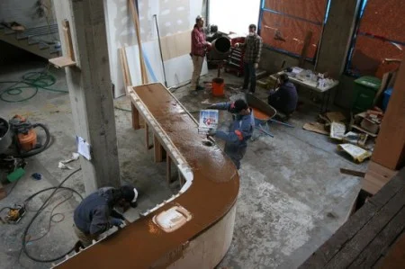 Concrete is a challenging medium-heavy, difficult to mix, (especially with additives) and tricky to achieve consistent finishes. The mold construction must be spot on because every blemish shows and the molds must be strong enough to withstand the vibration process. Vibration consolidates concrete in two stages: first by moving the concrete particles, then by removing entrapped air.
