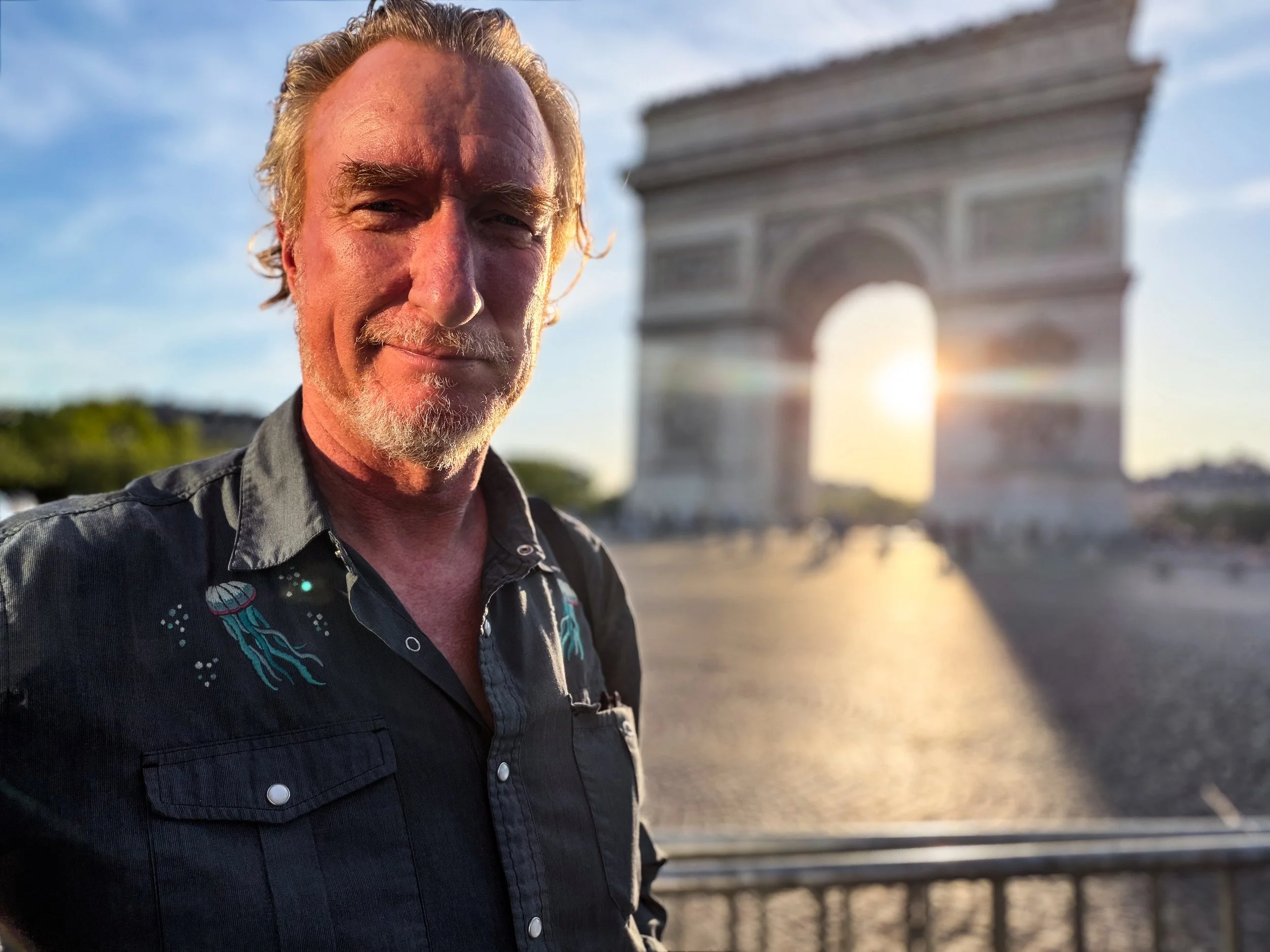 Robert Stribley standing before the Arc De Triomphe at sunset