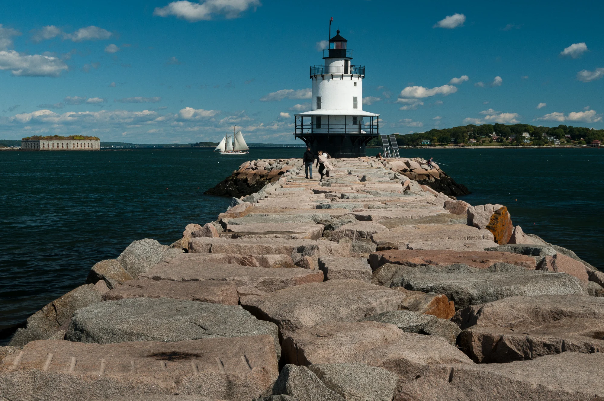 Spring Point Ledge Light, in South Portland, Maine, with view of Fort Gorges and white sailboat in the bay