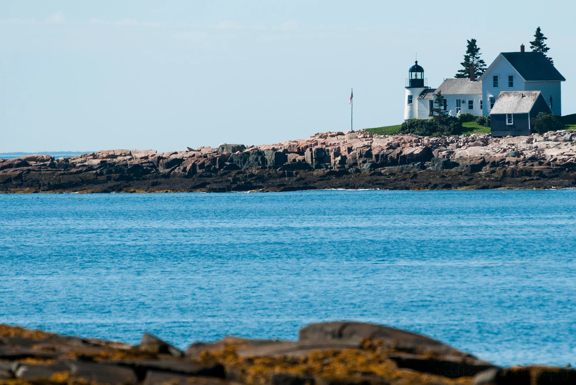 Winter Harbor Light, on Mark Island, Maine, seen from rocky coast of the Schoodic Peninsula portion of Acadia National Park