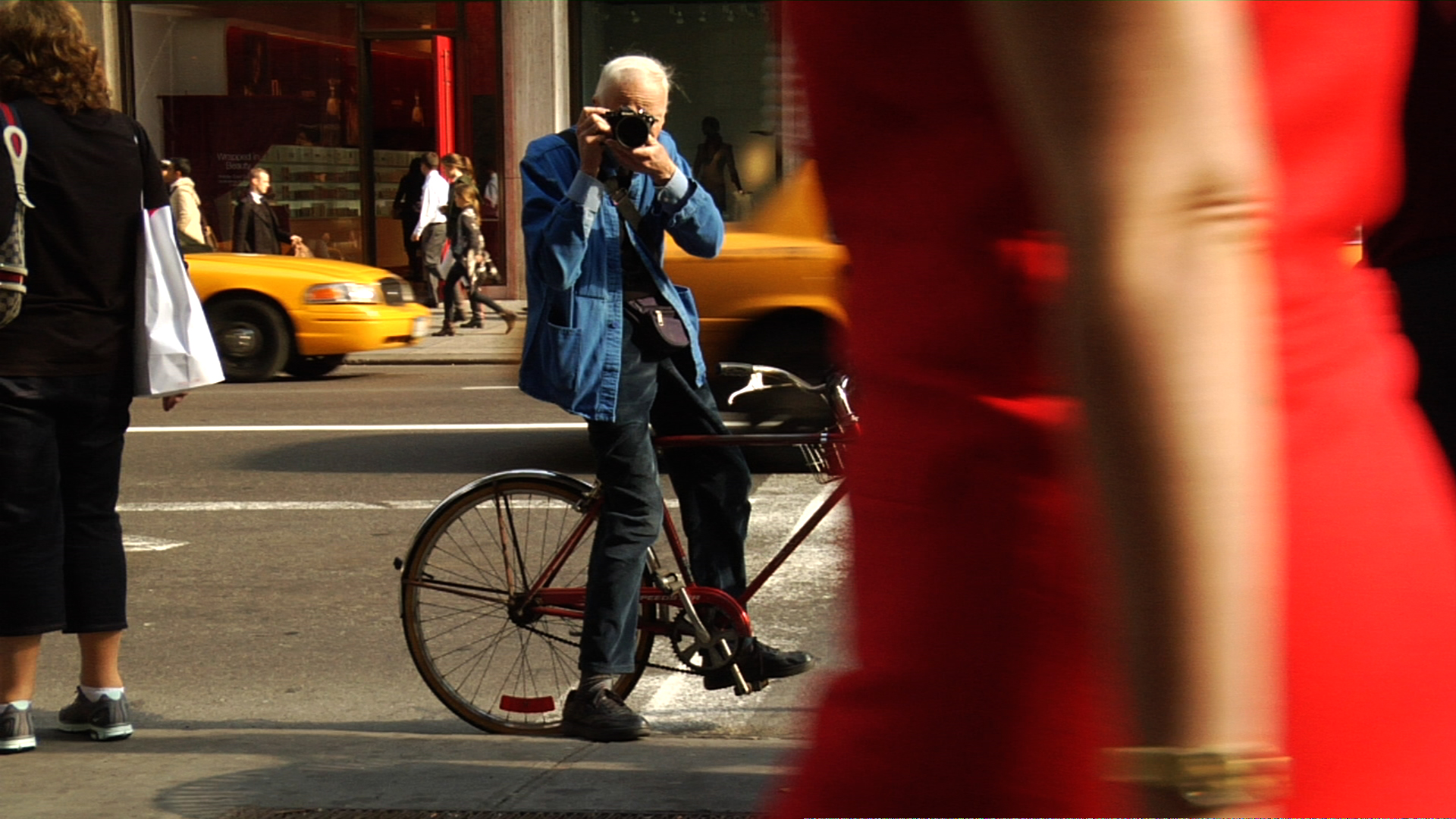 Bill Cunningham photographing in the street, in BILL CUNNINGHAM NEW YORK. A film by Richard Press. A Zeitgeist Films release. Photo credit: First Thought Films / Zeitgeist Films