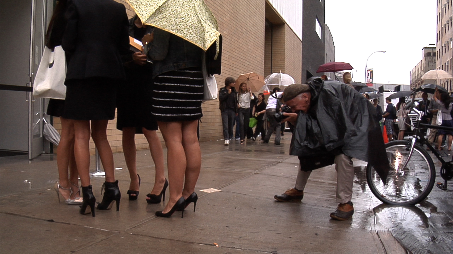 Bill Cunningham photographing in the street, in BILL CUNNINGHAM NEW YORK. A film by Richard Press. A Zeitgeist Films release. Photo credit: First Thought Films / Zeitgeist Films