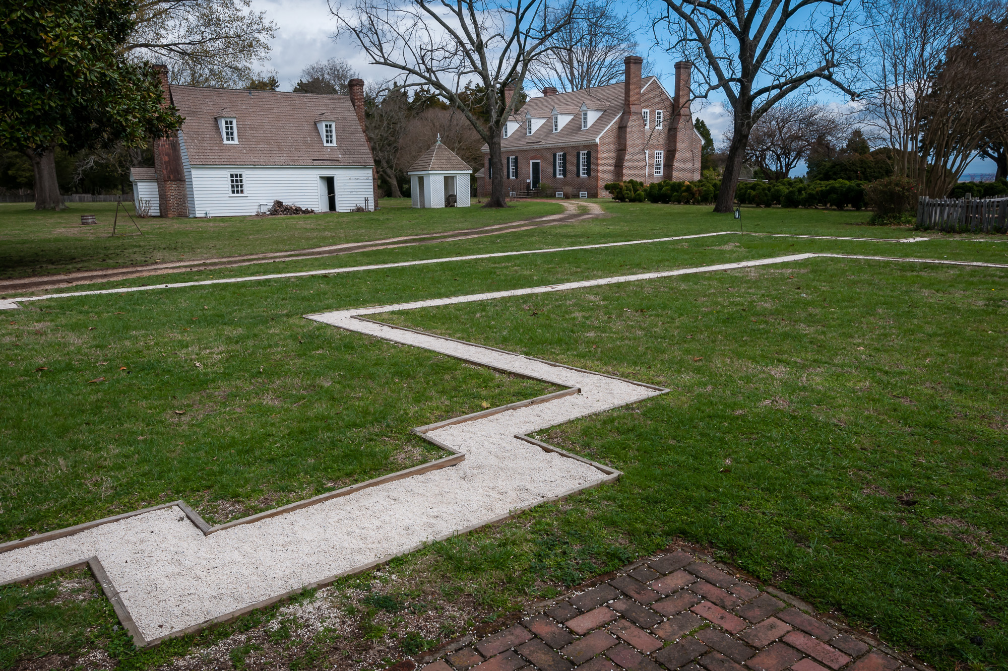 The outline of the original house, with the Memorial House and Colonial Kitchen in the background.