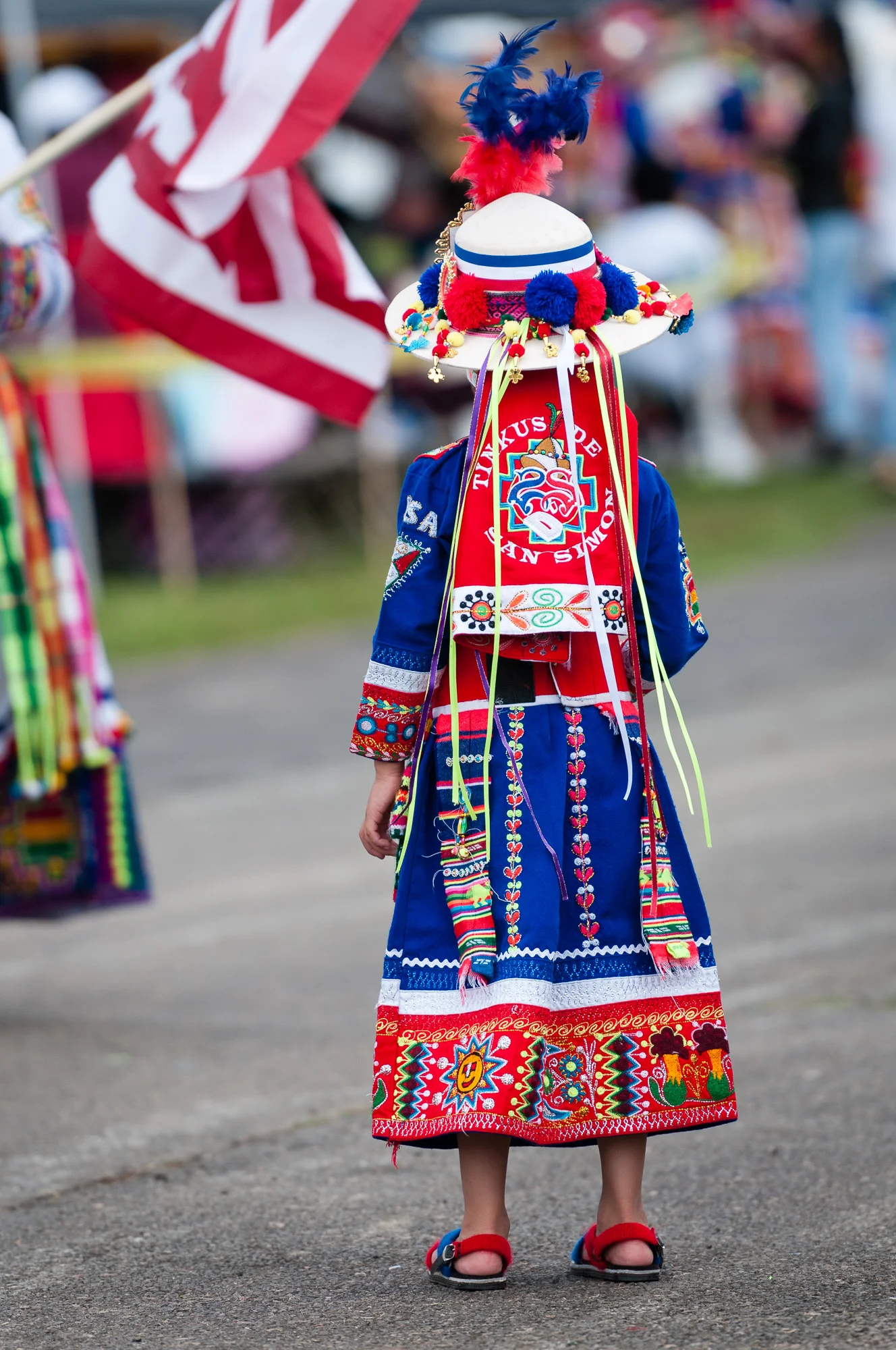 In this version I captured a lone young performer from Tinkus de San Simon USA, who had performed a Tinkus dance. She is facing away from me, looking towards the American flag and back towards the rest of her group. I really like the moments captured in these two images.