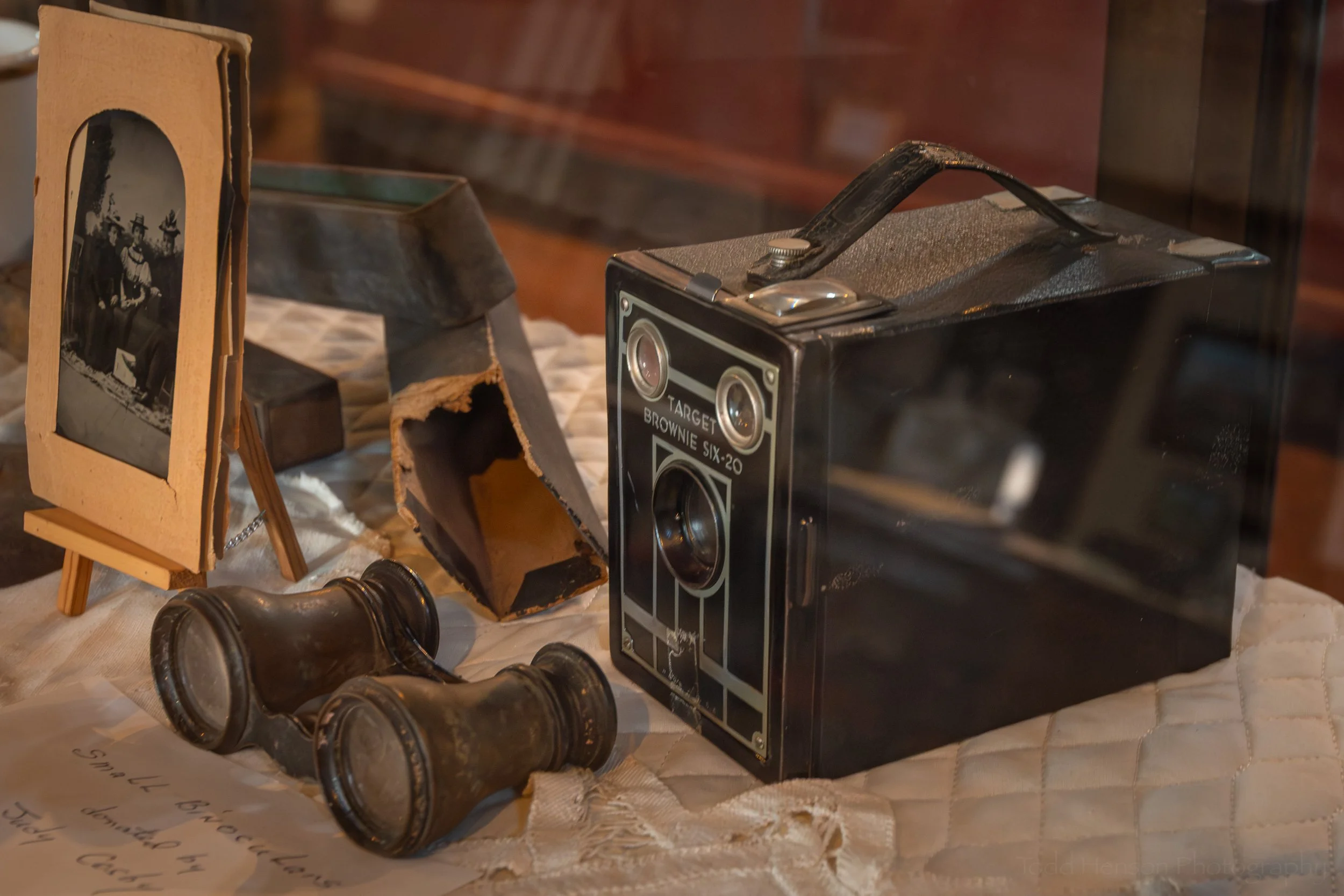 A Target Brownie Six-20 camera, small binoculars, and a photograph