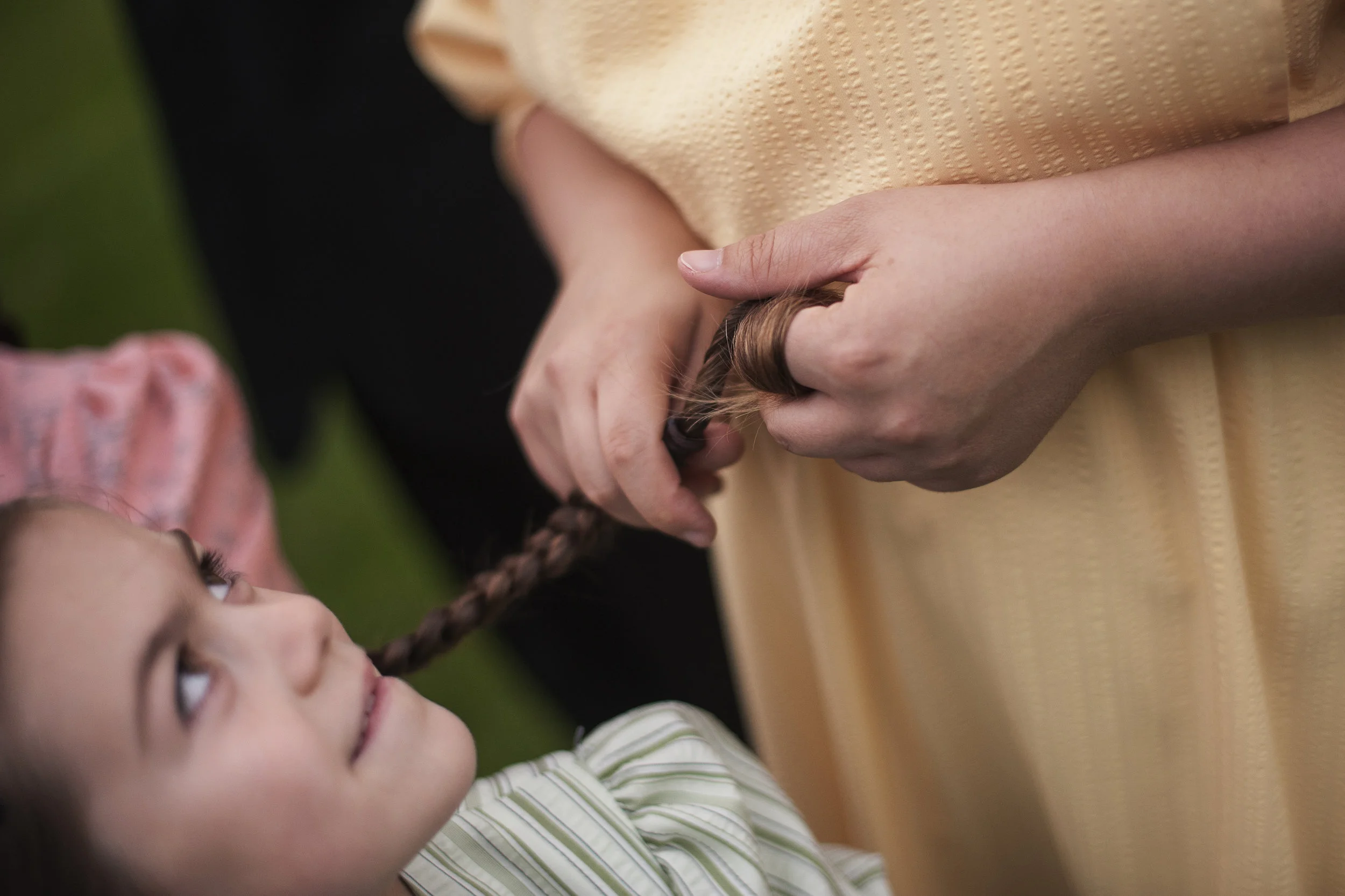 Chloe, 7, looks up at Freda as Freda twirls her hair during family portraits on Oct. 11 in Coleman, Mich. Freda often twirls the end of her daughters' braids without realizing it.