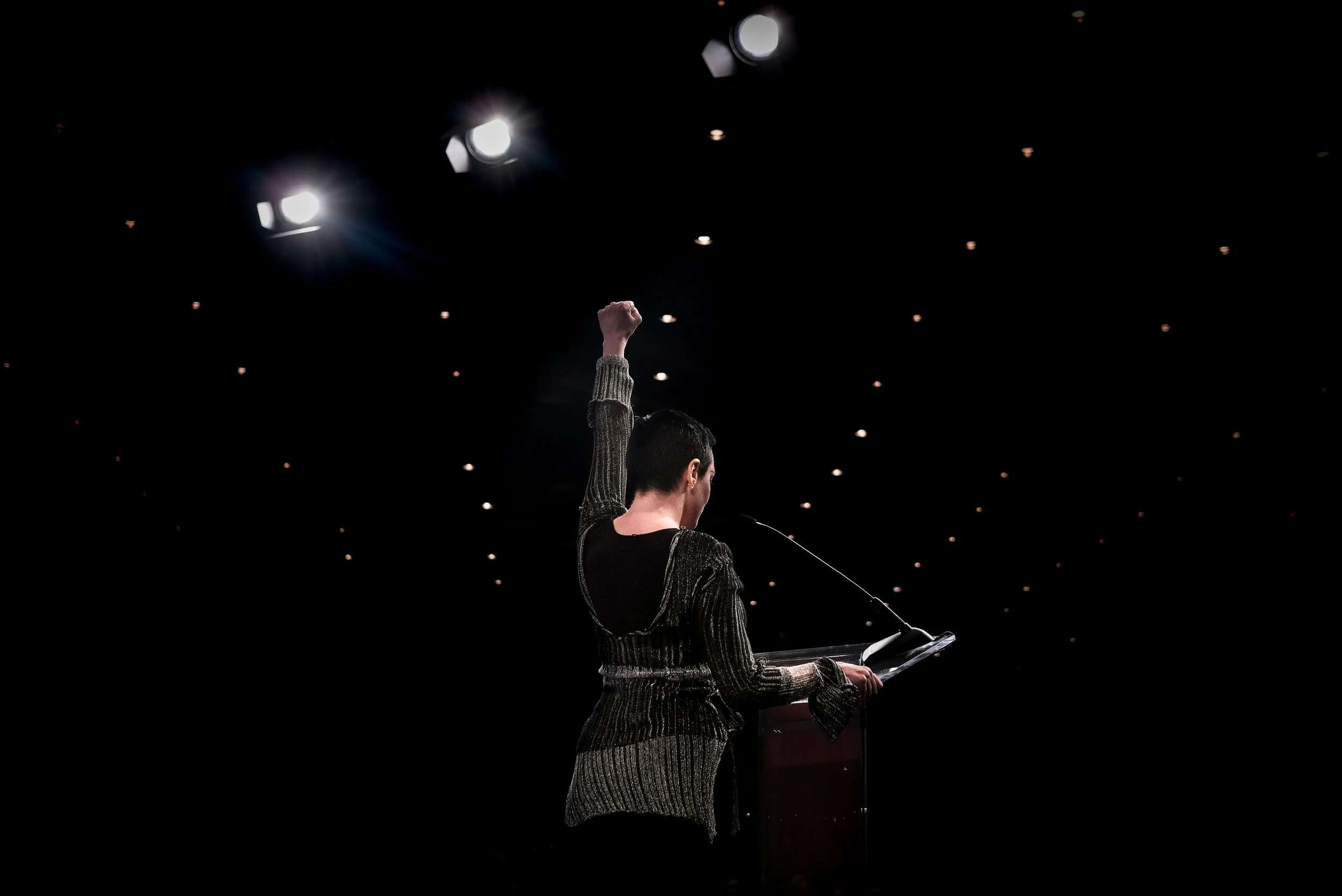 Actress Rose McGowan raises her fist while delivering the opening address at the Women's Convention on Friday, Oct. 27 at Cobo Center in Detroit, Mich. This was the first time McGowan had spoken in public since accusing film producer Harvey Weinstein of rape.