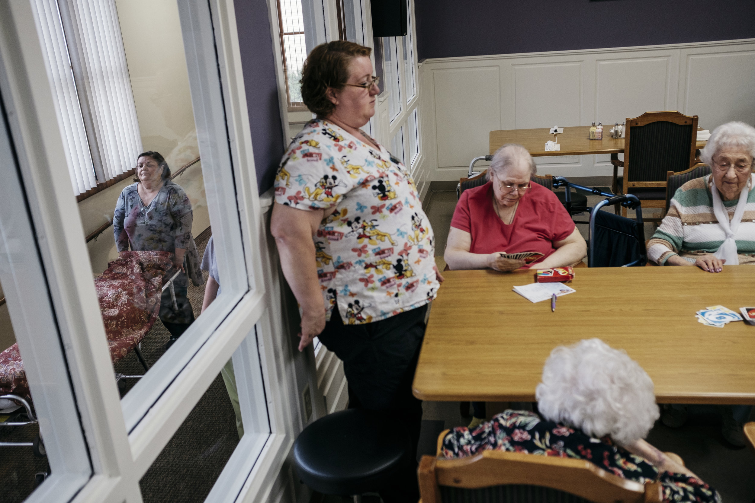  King's Daughters activity director Terra Hannon leads a game of UNO with Naomi Jean Harp, 77, and Lorene Kendall, 98, right, as a recently deceased resident's body is wheeled away on Tuesday, June 18, 2019 in Mexico, Mo. 