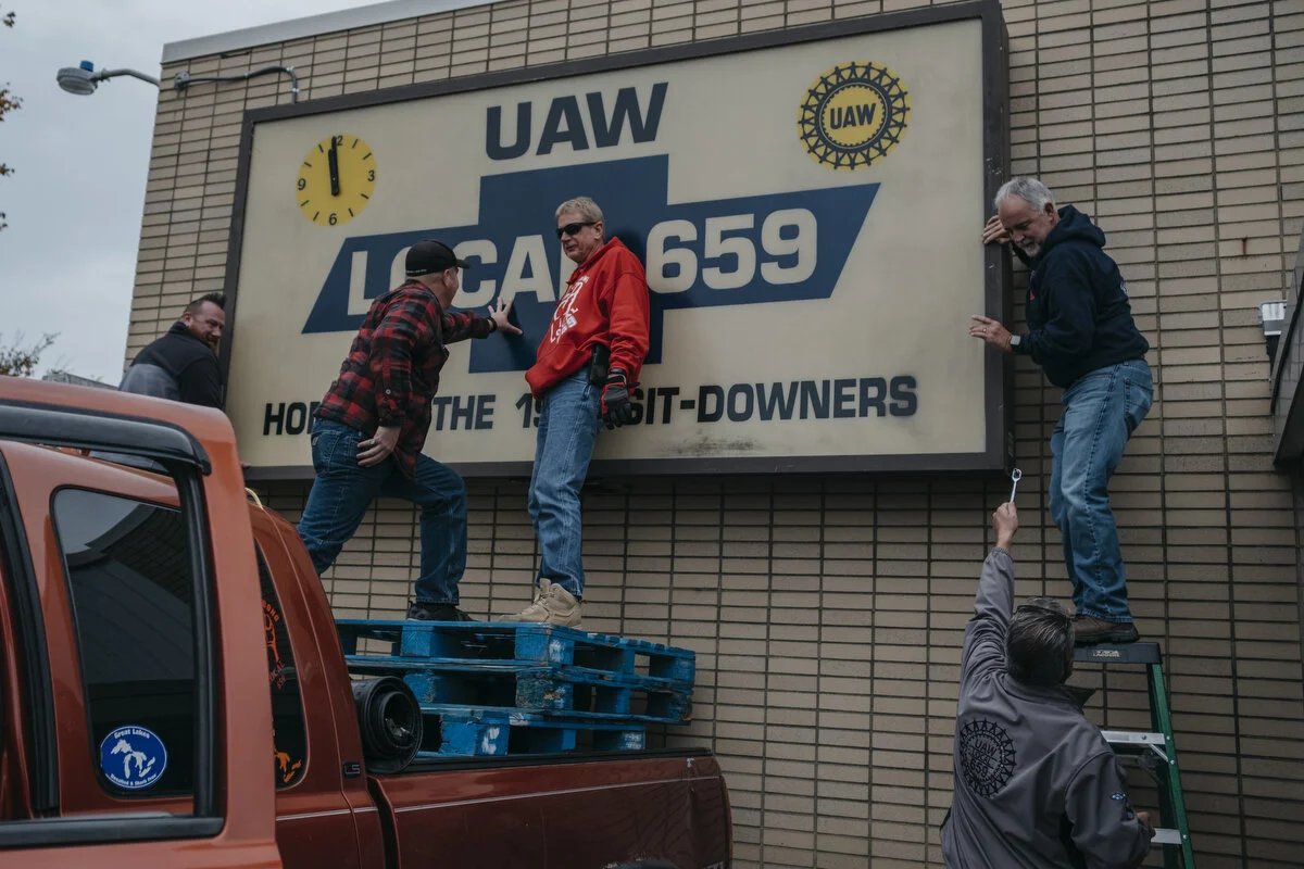  UAW Local 659 members hang their sign from 1956 on the front of the building in Flint, Mich. on Friday, Oct. 25, 2019. "We knew if we didn't do it on the last day of the strike it wouldn't get done," financial secretary Duane Ballard said. 