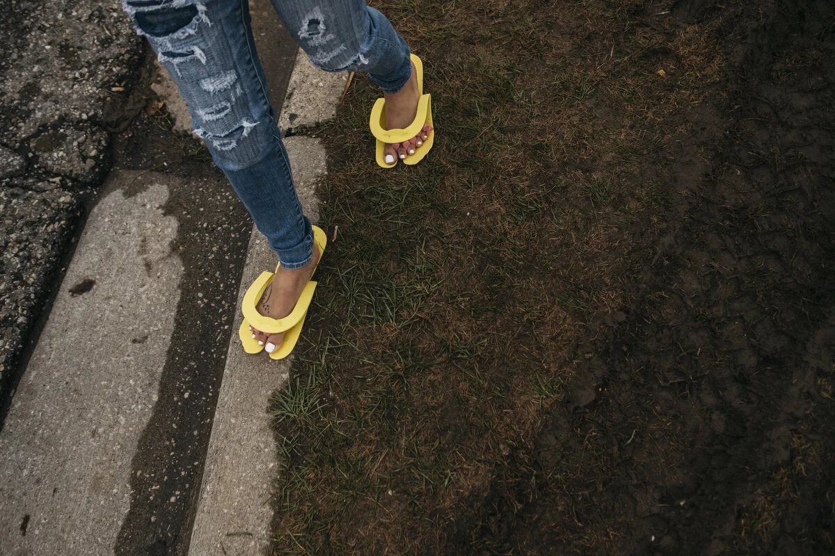  GM temporary employee Leaira Laury, 20, of Flint tries to avoid the mud with her newly painted toe nails while walking to picket outside the General Motors Flint Assembly Plant during the 18th day of the strike on Thursday, Oct. 3, 2019 in Flint, Mi