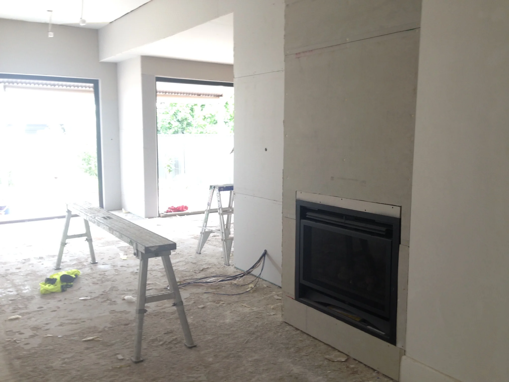 Plasterboard has gone up - and new fireplace installed in living room. You can just make out the black window frames across the kitchen and dining/living area.
