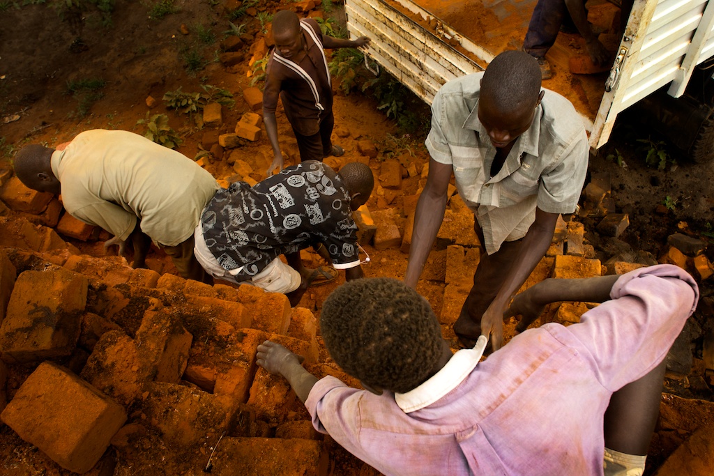 Karamoja workers transfer bricks onto a truck from a kiln pile near Kaabong, Uganda.