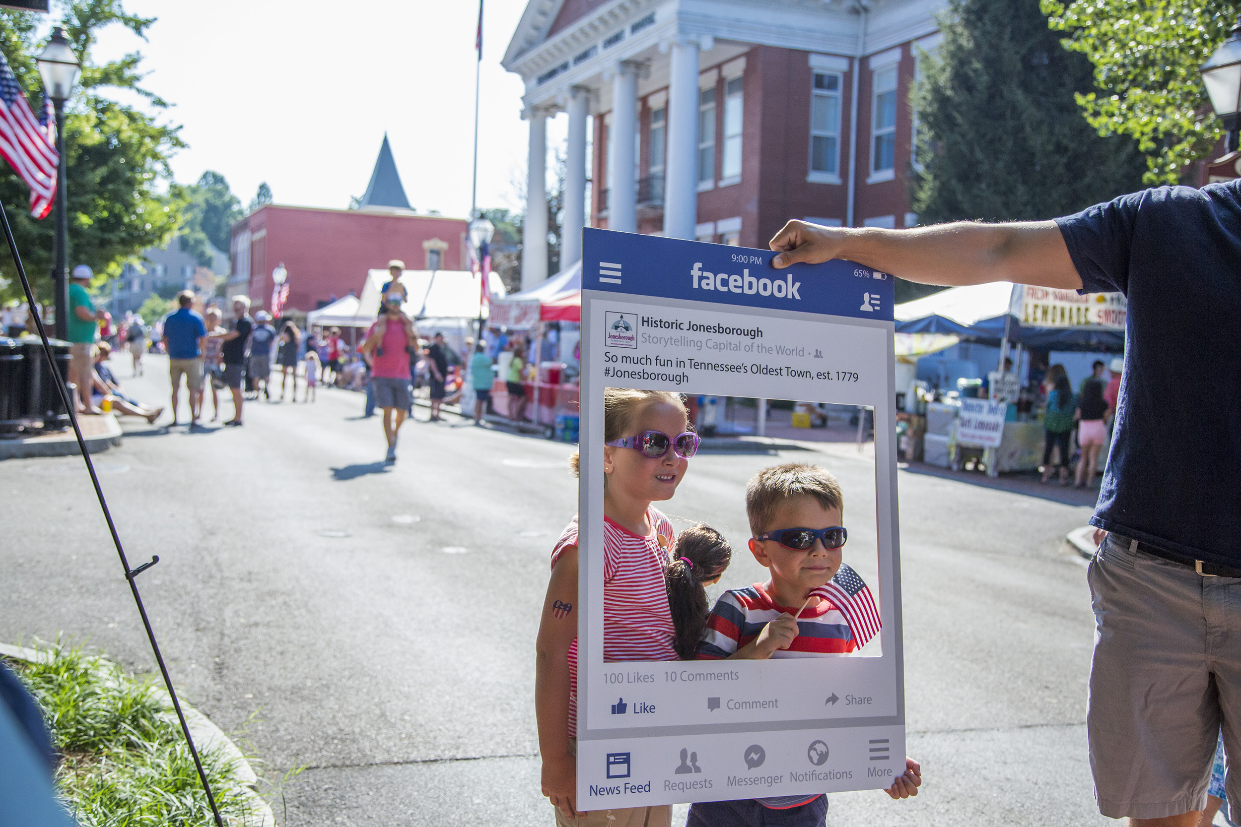 Children pose for a picture through a mock-post Facebook frame for Historic Jonesborough.