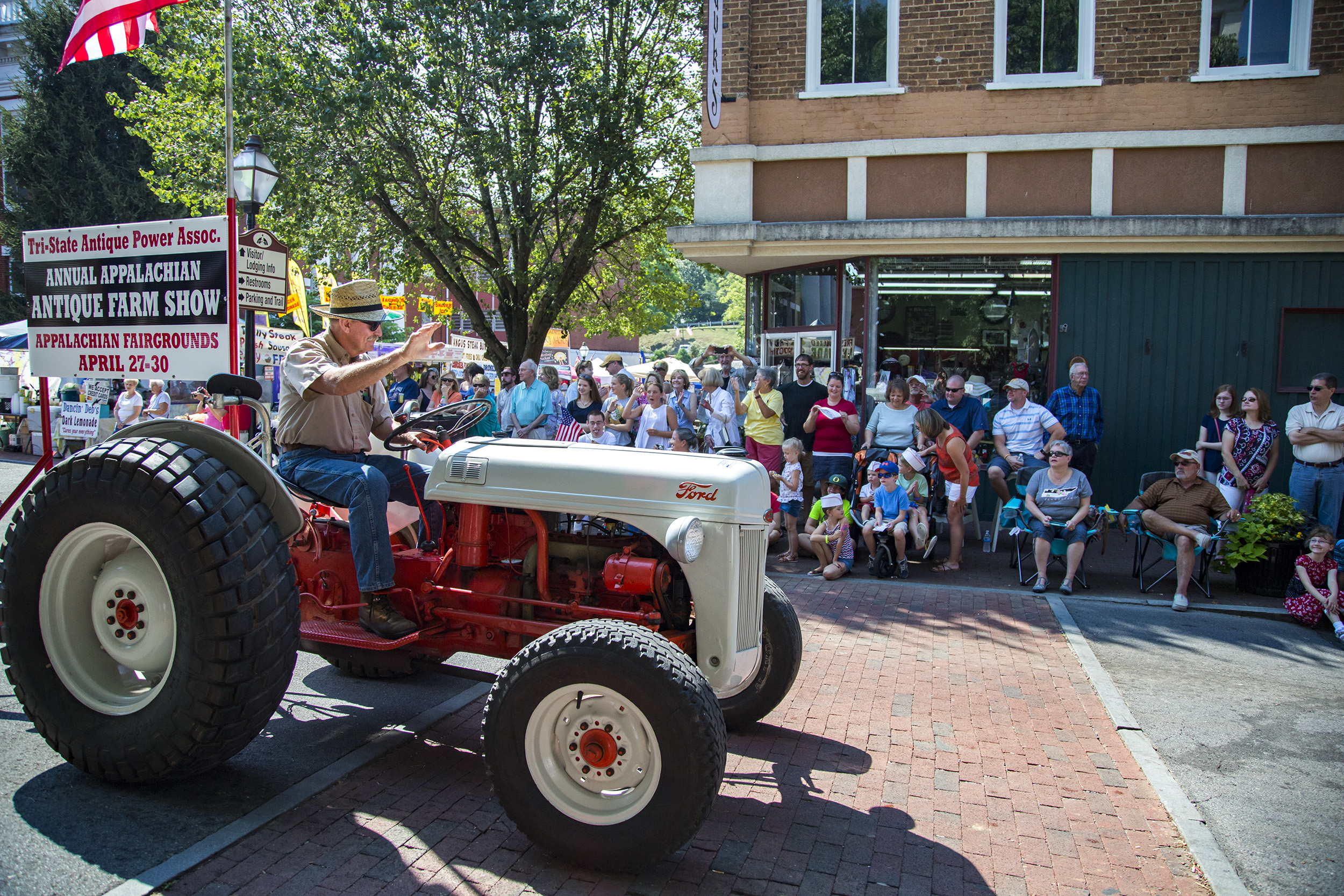 The crowd cheers and laughs as a man honks the horn of his tractor. Jonesborough, Tennessee.