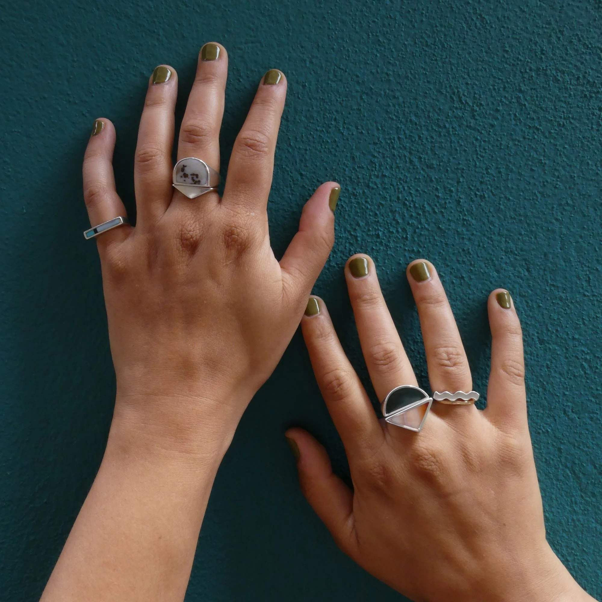 multi rings on teal background woman hand.JPG