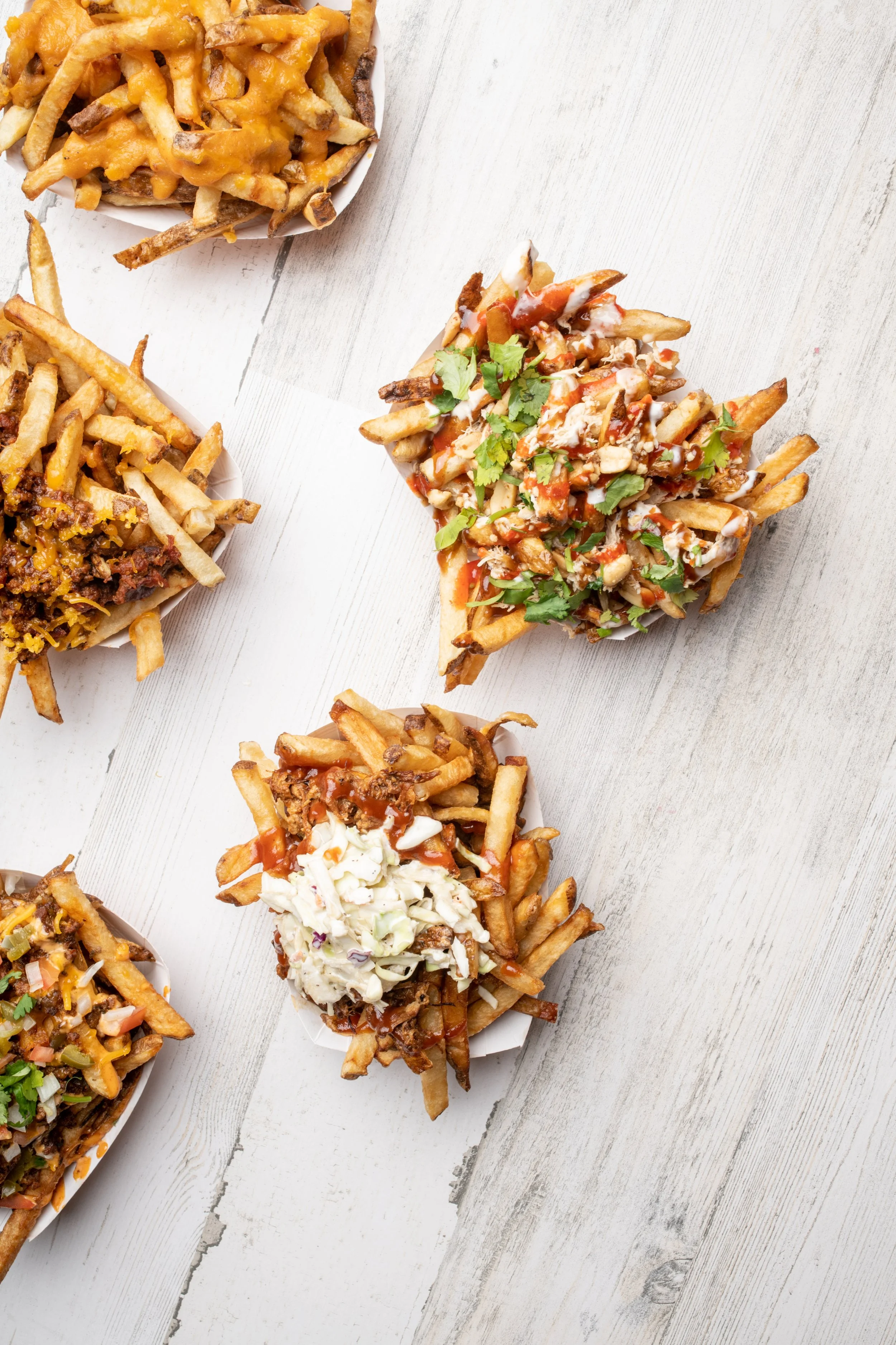 Assorted loaded fries topped with cheese, sour cream, shredded chicken, and cilantro.