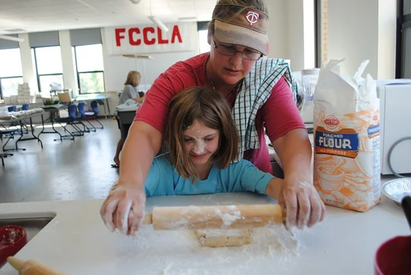 Lois Schulz shows Lily Adkins how to roll out her pie crust during the Bake and Take Camp, sponsored by WDCB Community Education.