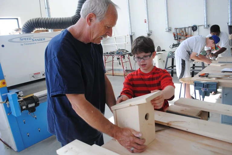 Sean Carlson places the top of his birdhouse while Mike Holzer holds it.