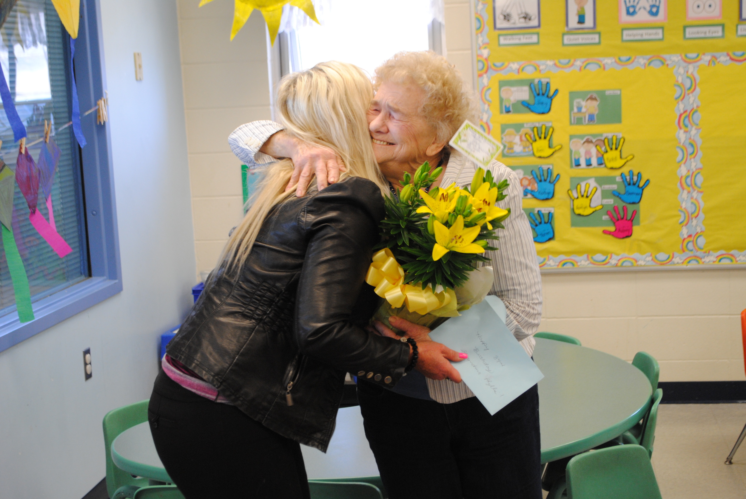 Phyllis Jackson, right, gives Kids Club Director, Tracy Dreger, a big hug after she received a beautiful day lily and birthday card from staff on Thursday.