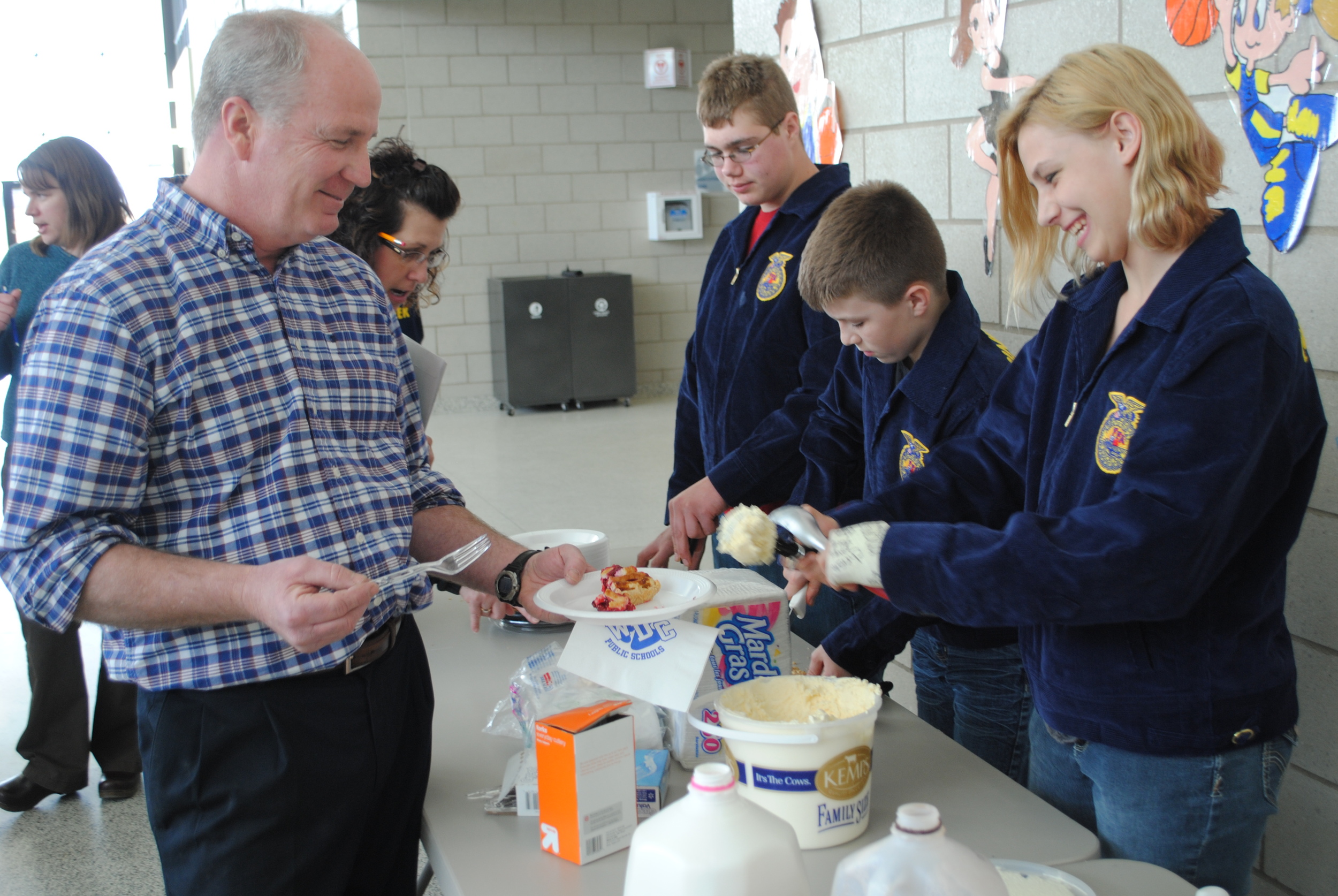 WDC fifth-grade teacher Dave Sea watches as FFA member Barb Zick carefykkt scoops up vanilla ice cream for Sea's cherry pie during the FFA chapter's Cherry Pie Social. Also pictured serving pie are FFA members Ethan Benson, left, and Ryan Grendahl. (Photos by Dana Pavek, WDC Schools)
