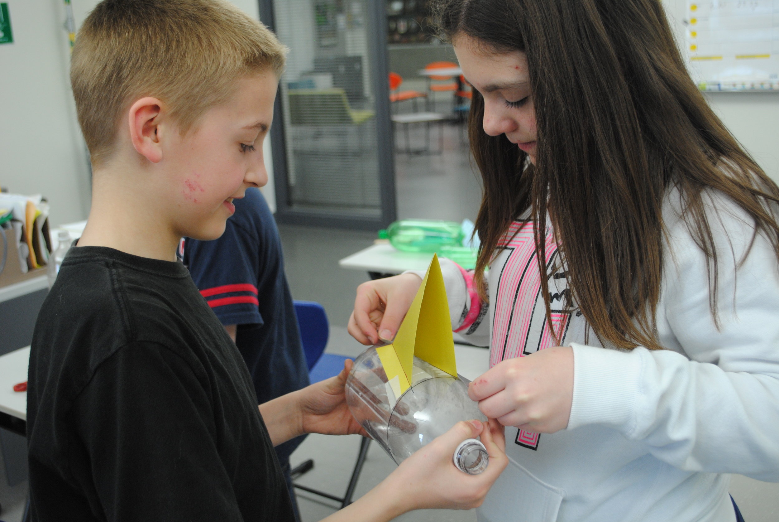 Building the bottle rockets sometimes requires help from a classmate. Above, Elliot Doyle, left, holds the bottle while Joslynn Judd positions the fin. 