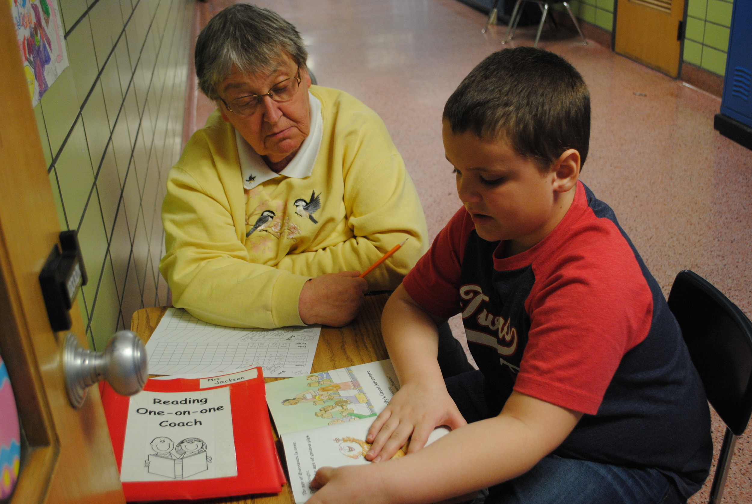 Reading one-on-one coach Carol Klindworth listens to a student read. The coaches help students improve their reading skills -- a valuable service to WDC students. (Photo by Dana Pavek, WDC Schools) 