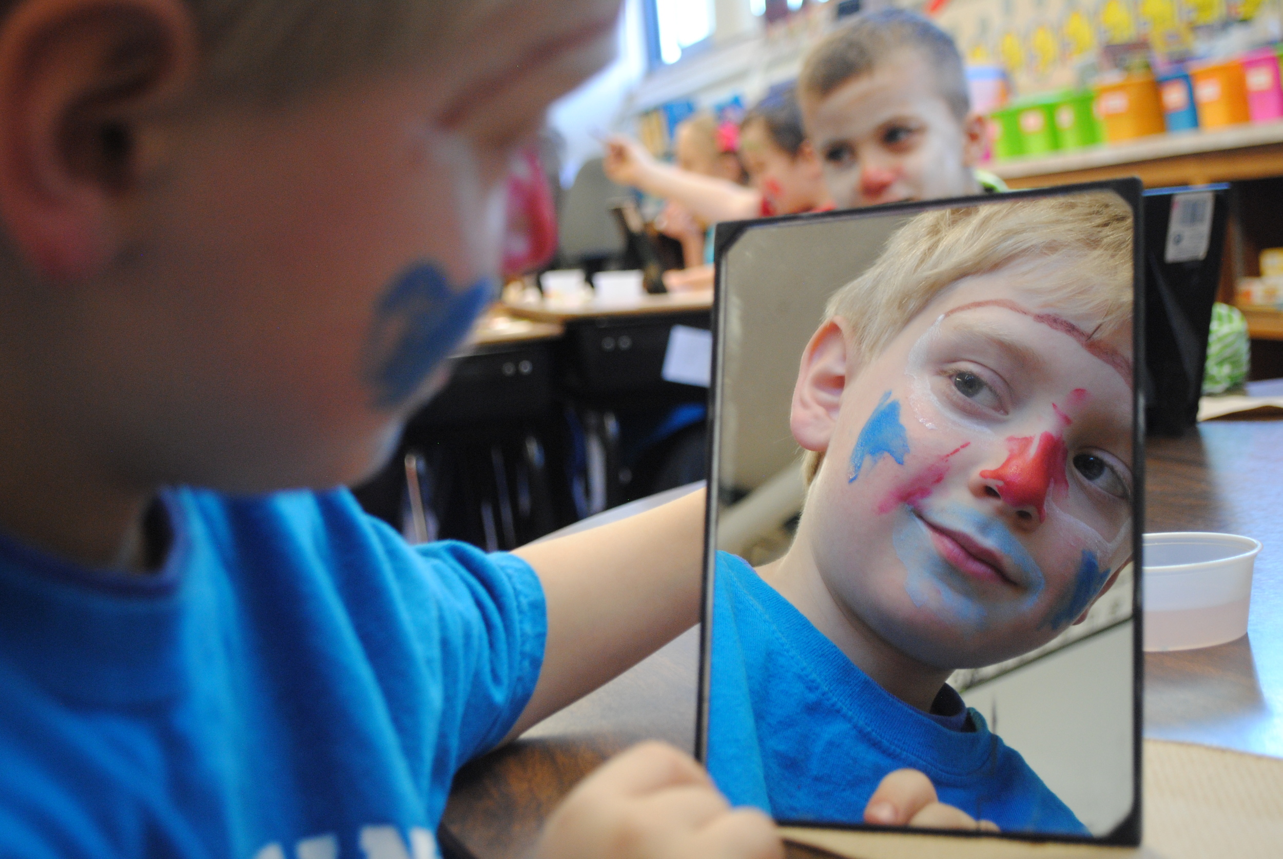 Christopher Davis admires his handiwork while applying clowning make-up on Friday, March 13. First-graders were getting ready for their clowning performance that afternoon. 