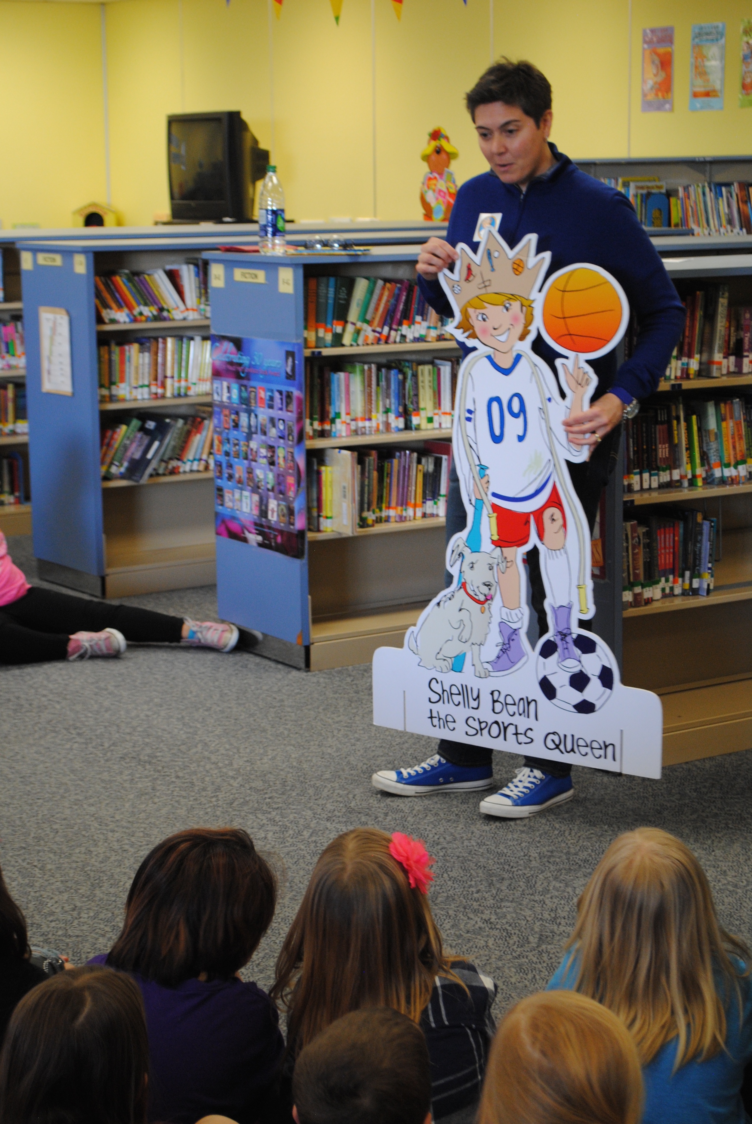 Author Shelly Boyum-Breen shows Wadena-Deer Creek students a cardboard cutout of Shelly Bean -- a sporty, dirty-kneed little girl with a “can-do” spirit.