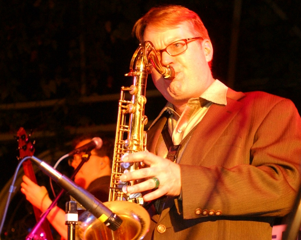    A man playing the saxophone at night.   