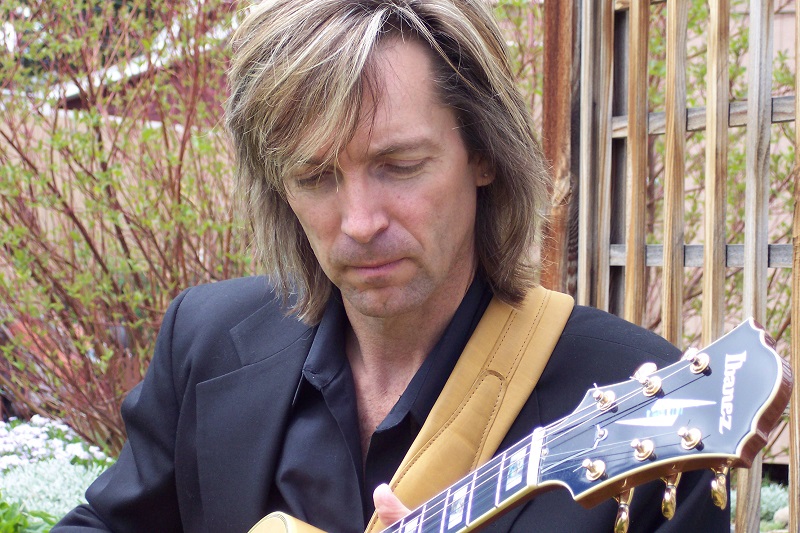    Bill Sickles playing semi hollow body guitar in park venue in Littleton Colorado.   