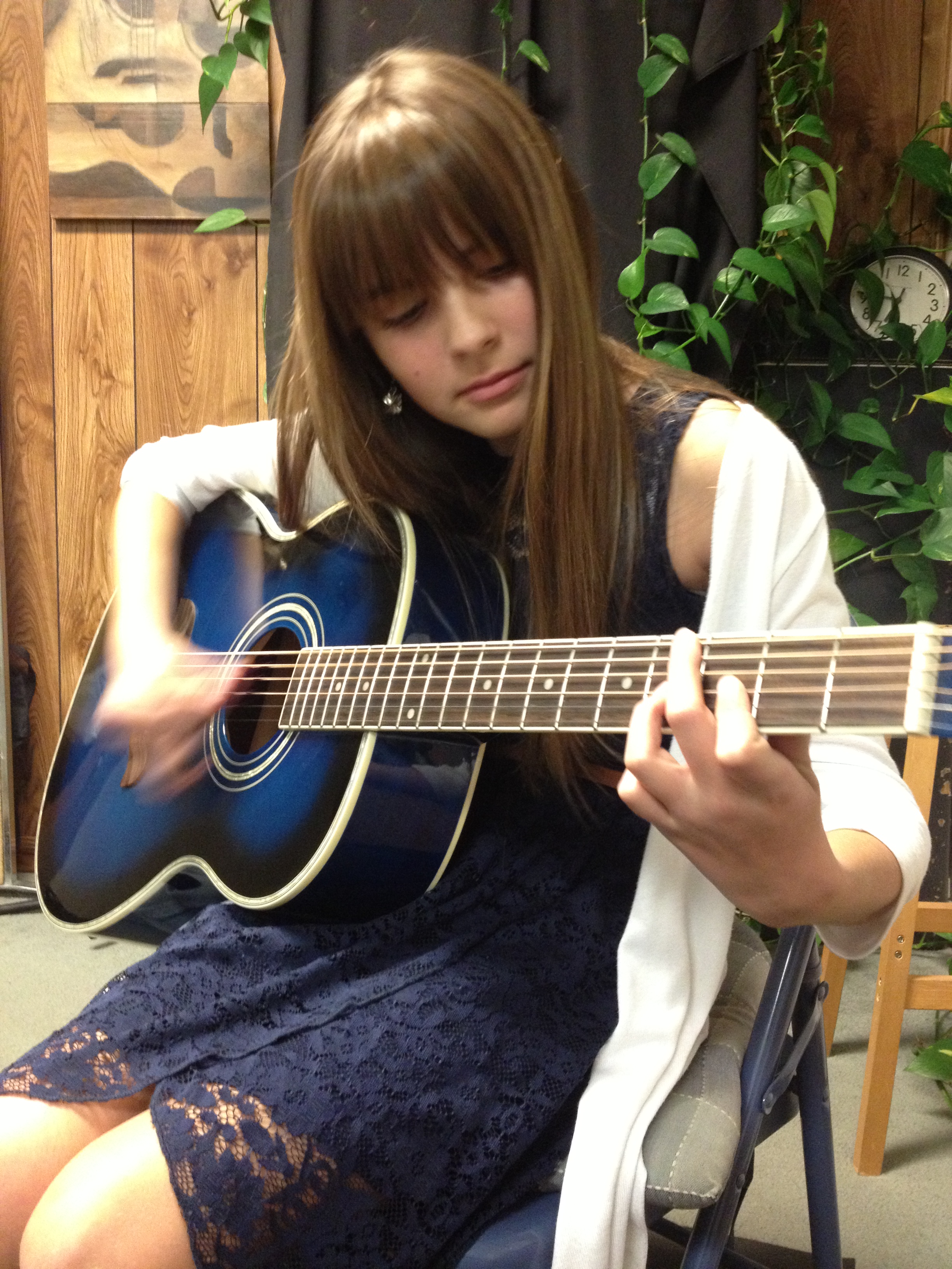    Teen girl plays the guitar chords.   