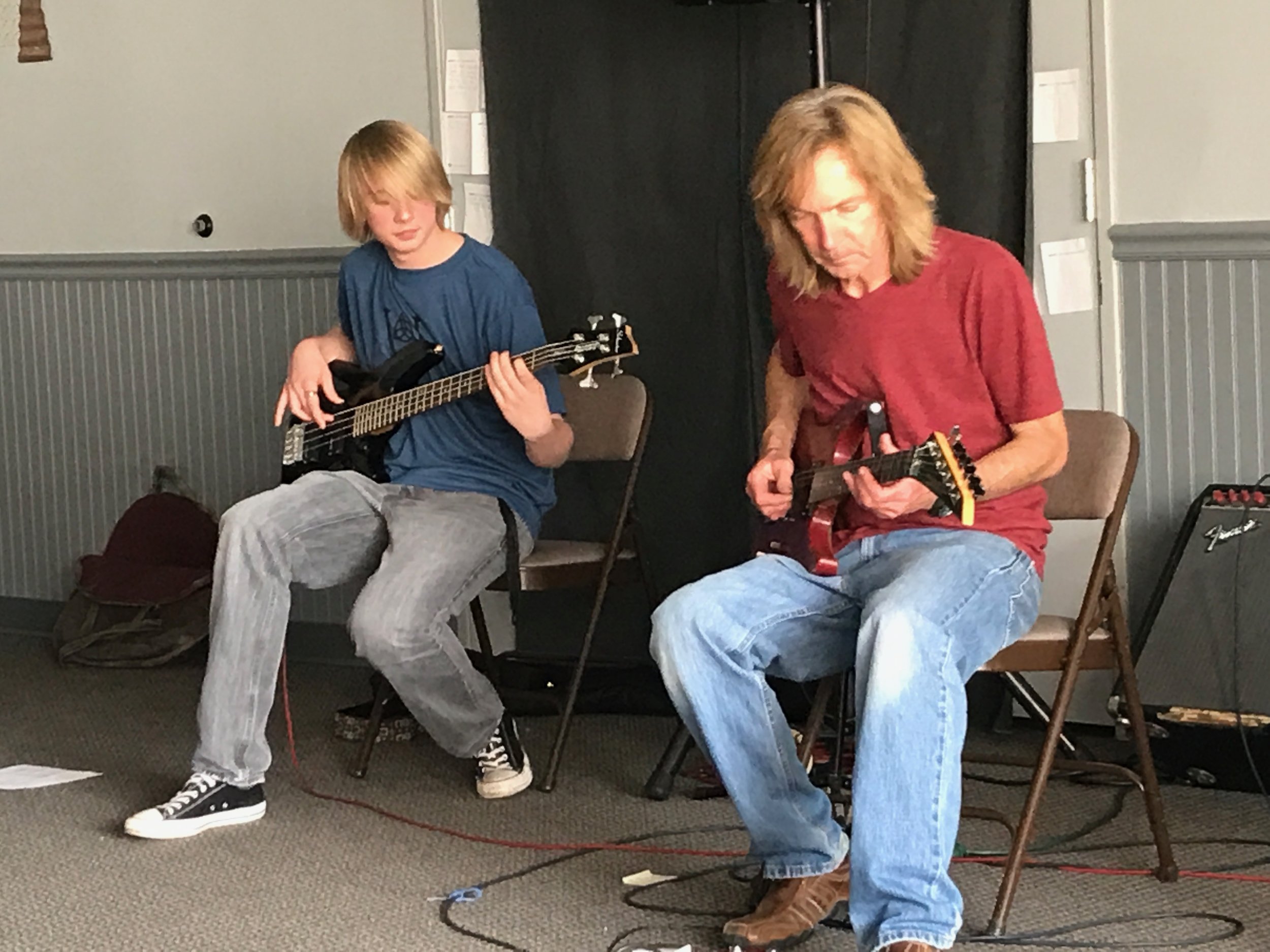    Teen and teacher practice a duet on electric guitars.   