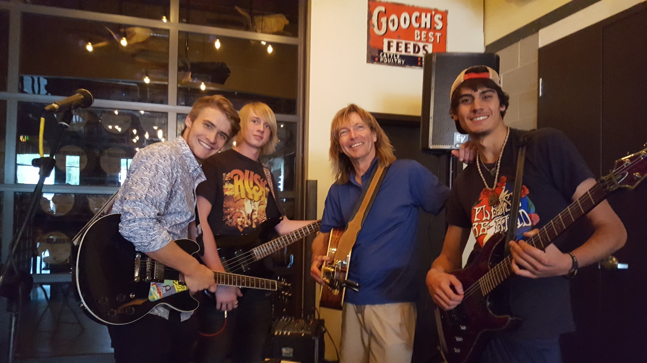    Teen electric guitar students perform with teacher.   