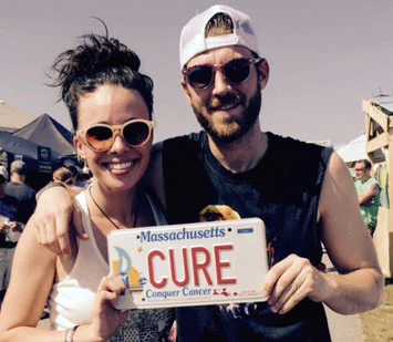 Chelsea and Jon pose with the traveling 'Cure' plate