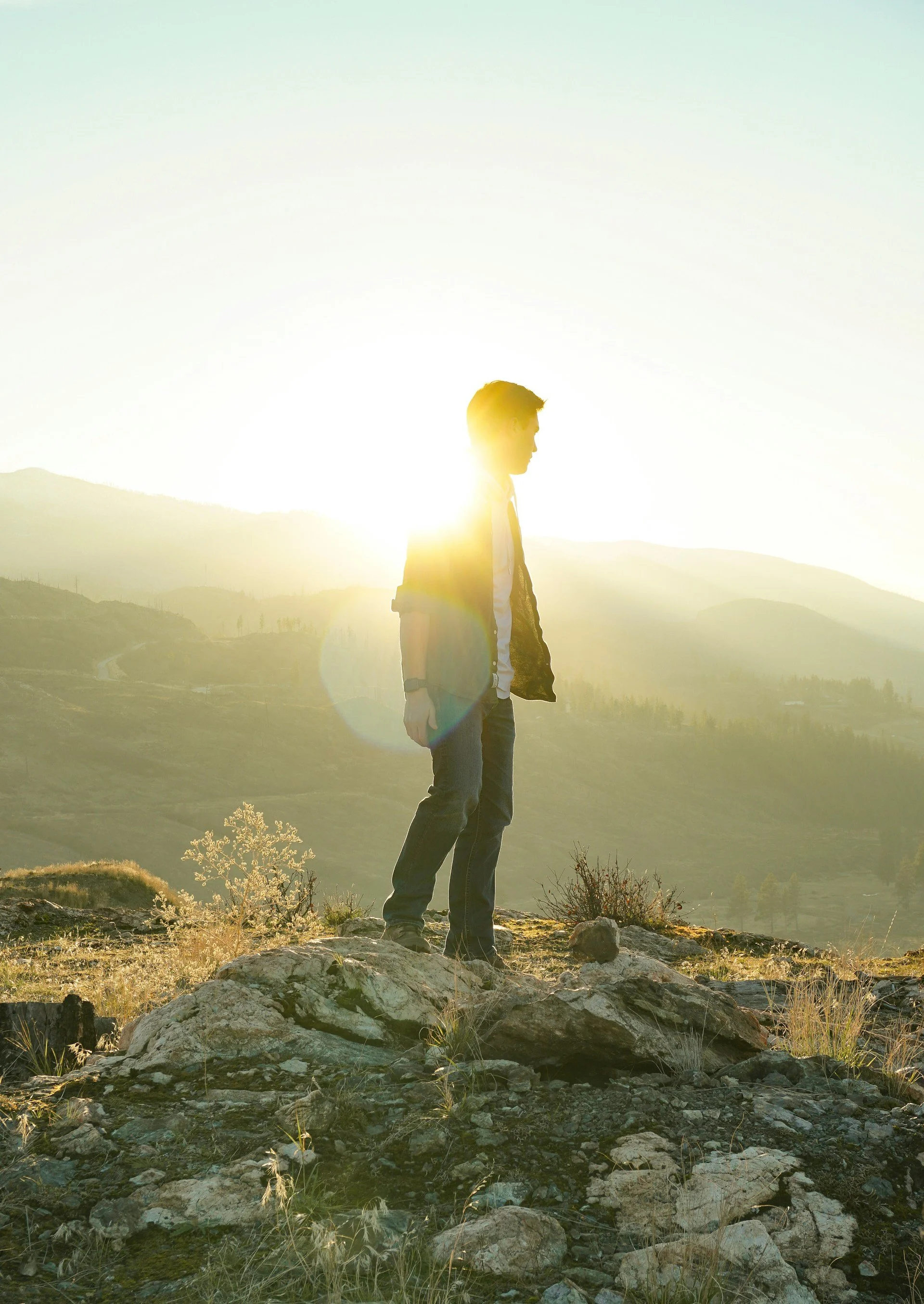 Man standing on a rocky hillside overlooking the mountains