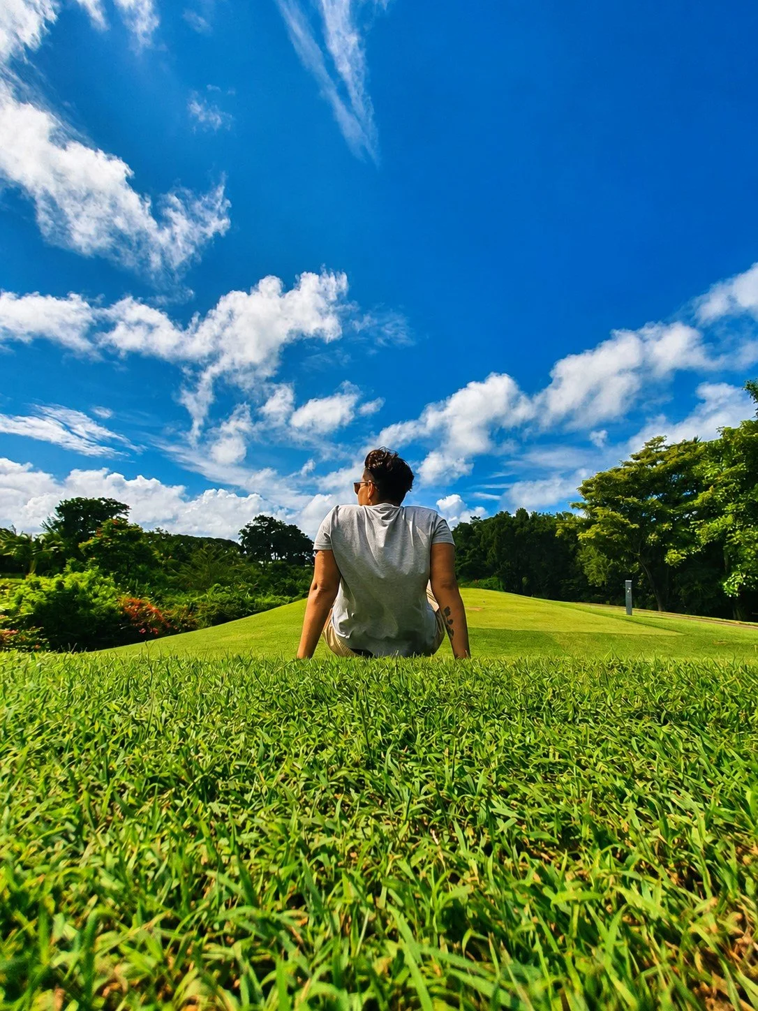 Person sitting on the grass under a blue sky