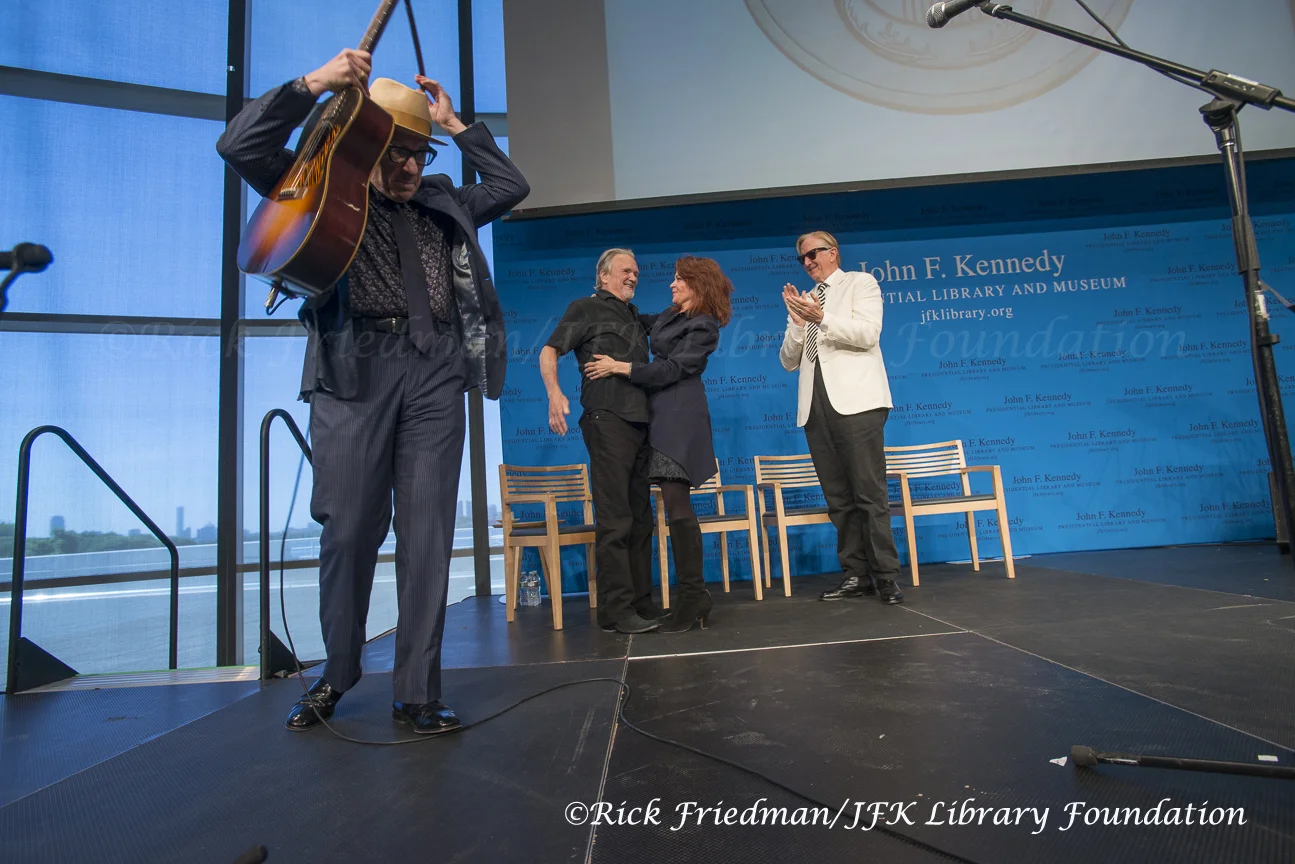 Rosanne Cash hugs Kris Kristofferson after Elvis Costello finishes performing. T. Bone Burnett on right.