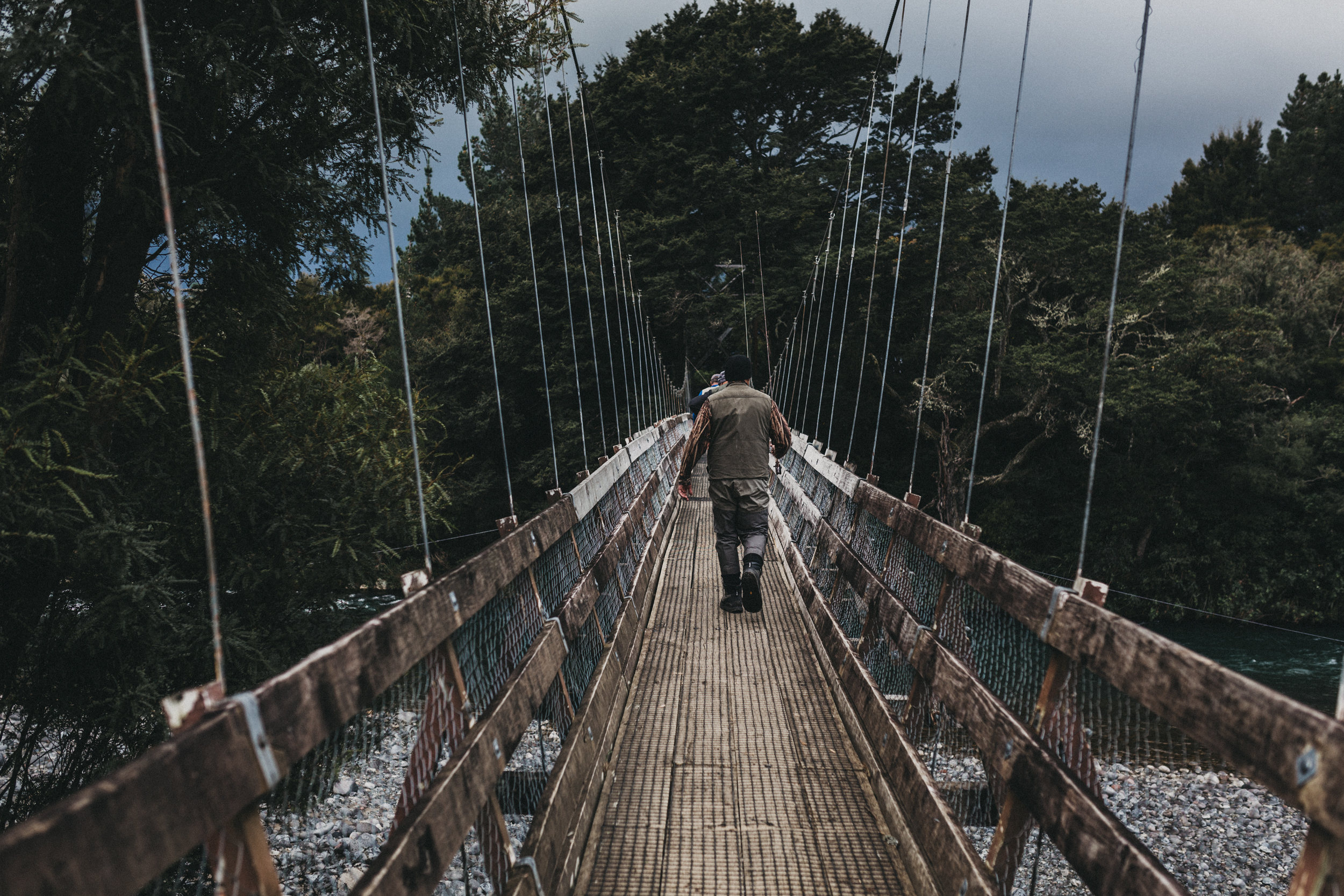 Day Two: a trout fisher crosses a bridge in Turangi with stormy skies looming.