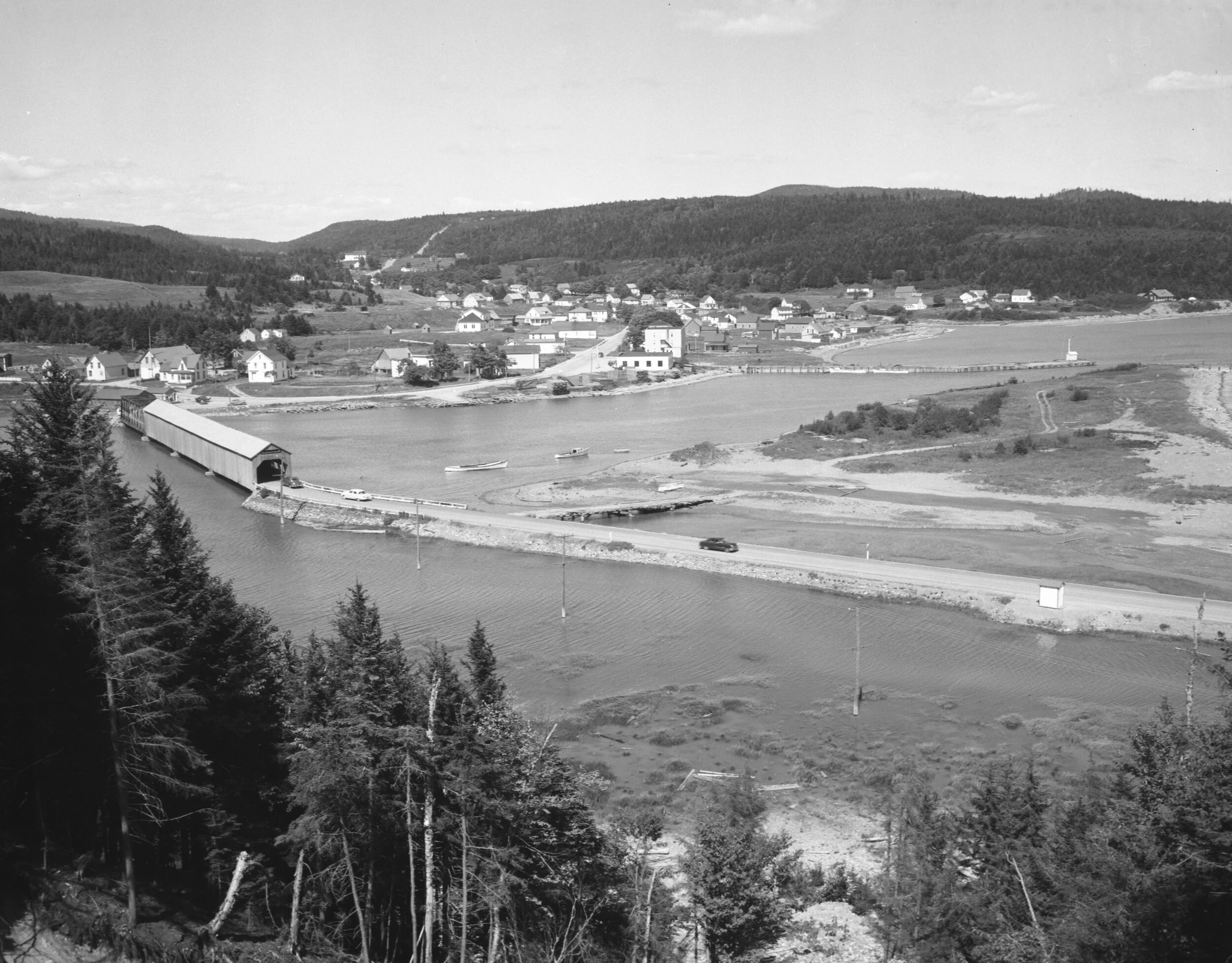 View from Hillside of covered bridge, shoreline and the town of Alma in the background, c.1950. From Archives New Brunswick P93-AL-223.