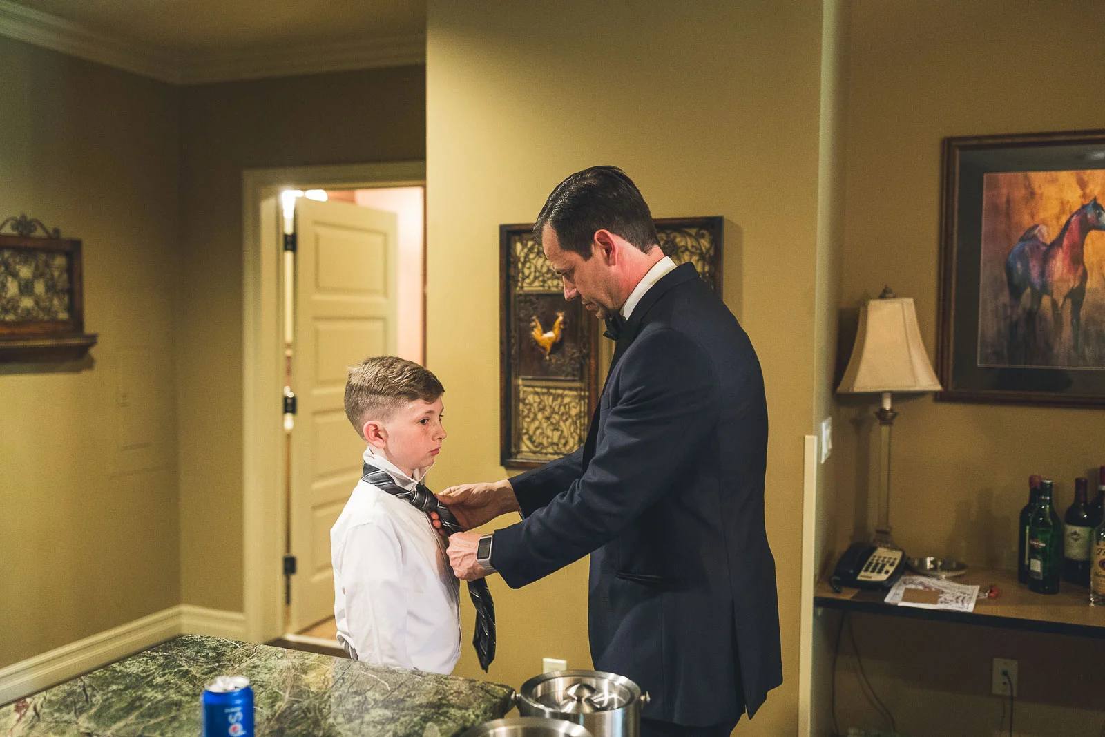 Groom helping young one with tie